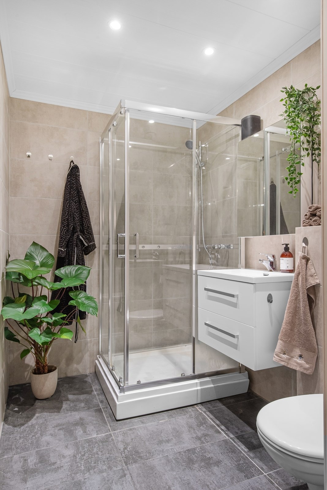 Badet har flislagte overflater, gulvvarme og downlights. Innredningen består av bla.a. dusjkabinett, servantinnredning og speilskap. Galleribilde