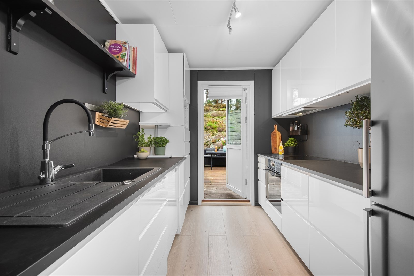 Innredningen har hvite, blanke fronter og benkeplate i laminat, og rommet ble malt i 2024. Herfra er det utgang til en skjermet terrasse på baksiden av boligen. Galleribilde