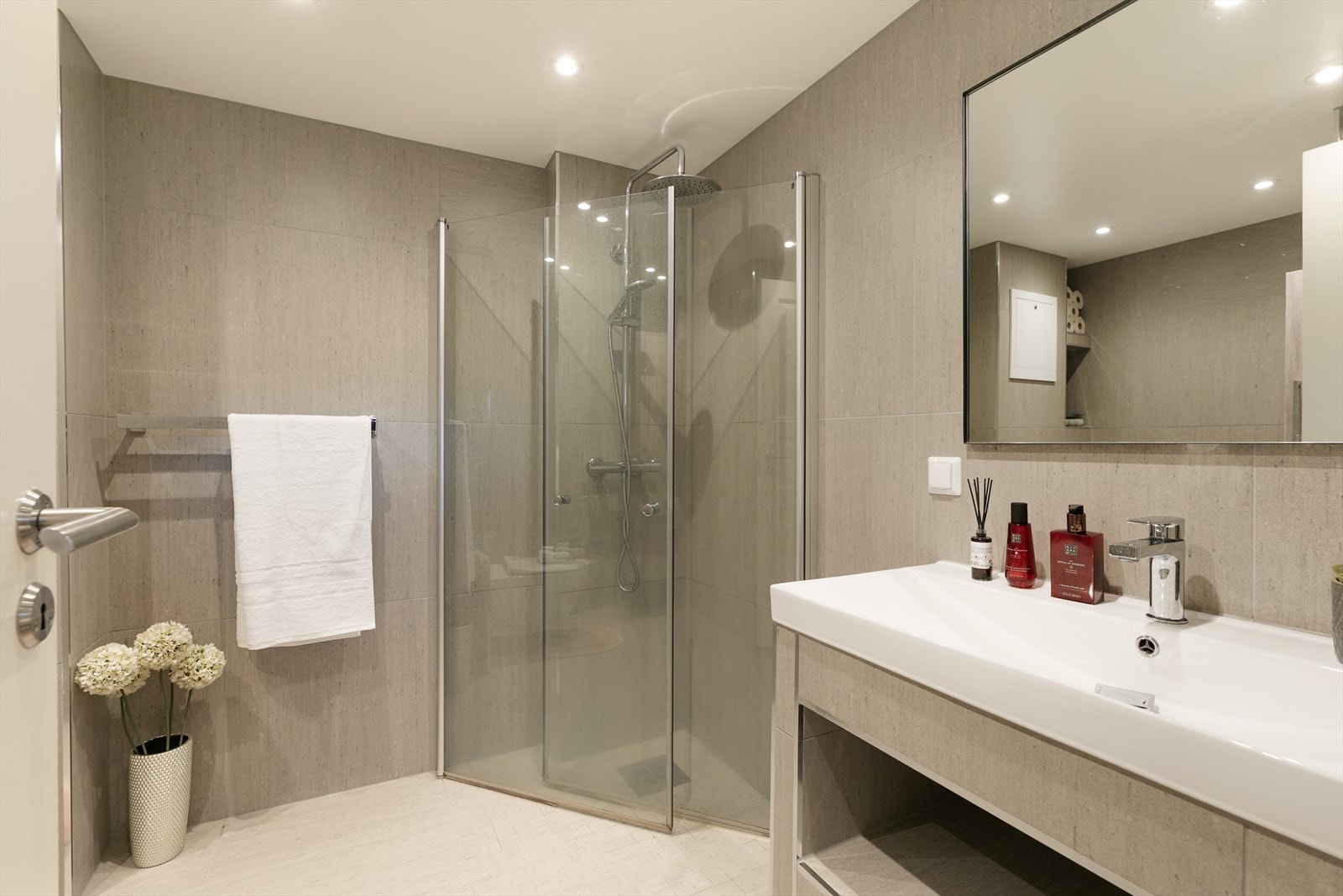 Badet består av varmekabler i gulv, vegghengt toalett, servant med oppbevaringshyller, dusjhjørne med glassdører og høyskap Galleribilde