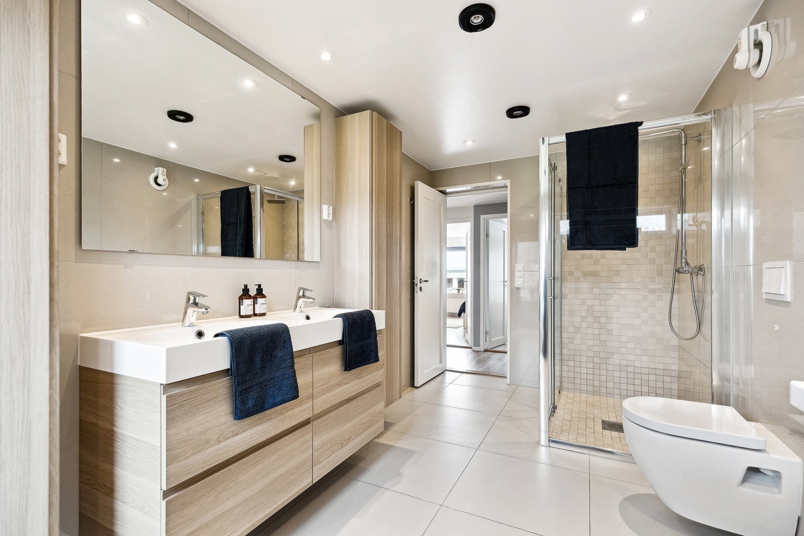 Det ca. 9,5 kvm store badet er stilrent innredet med tidløse fliser på vegger og gulv. Badet er utstyrt med en pen baderomsinnredning med romslige skuffeseksjoner, veggskap og dobbel servant. Galleribilde