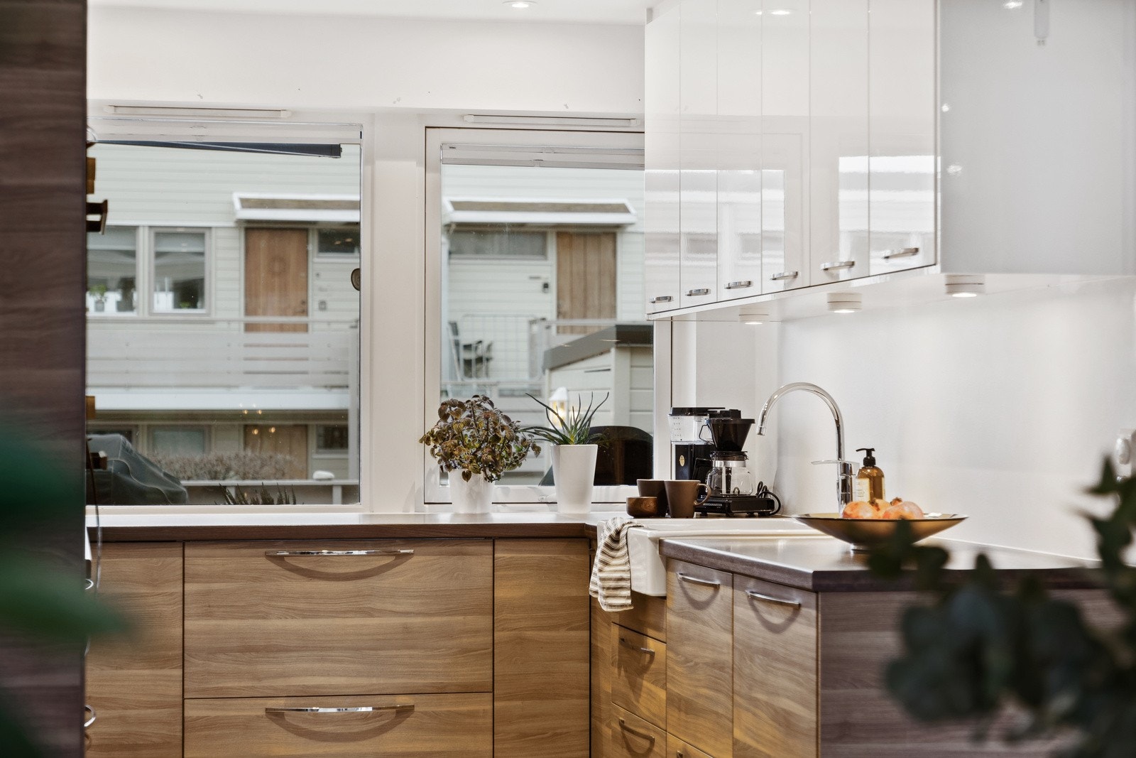 De naturtro tredetaljene i valnøtt står i behagelig kontrast til overskapene i høyglans. Galleribilde