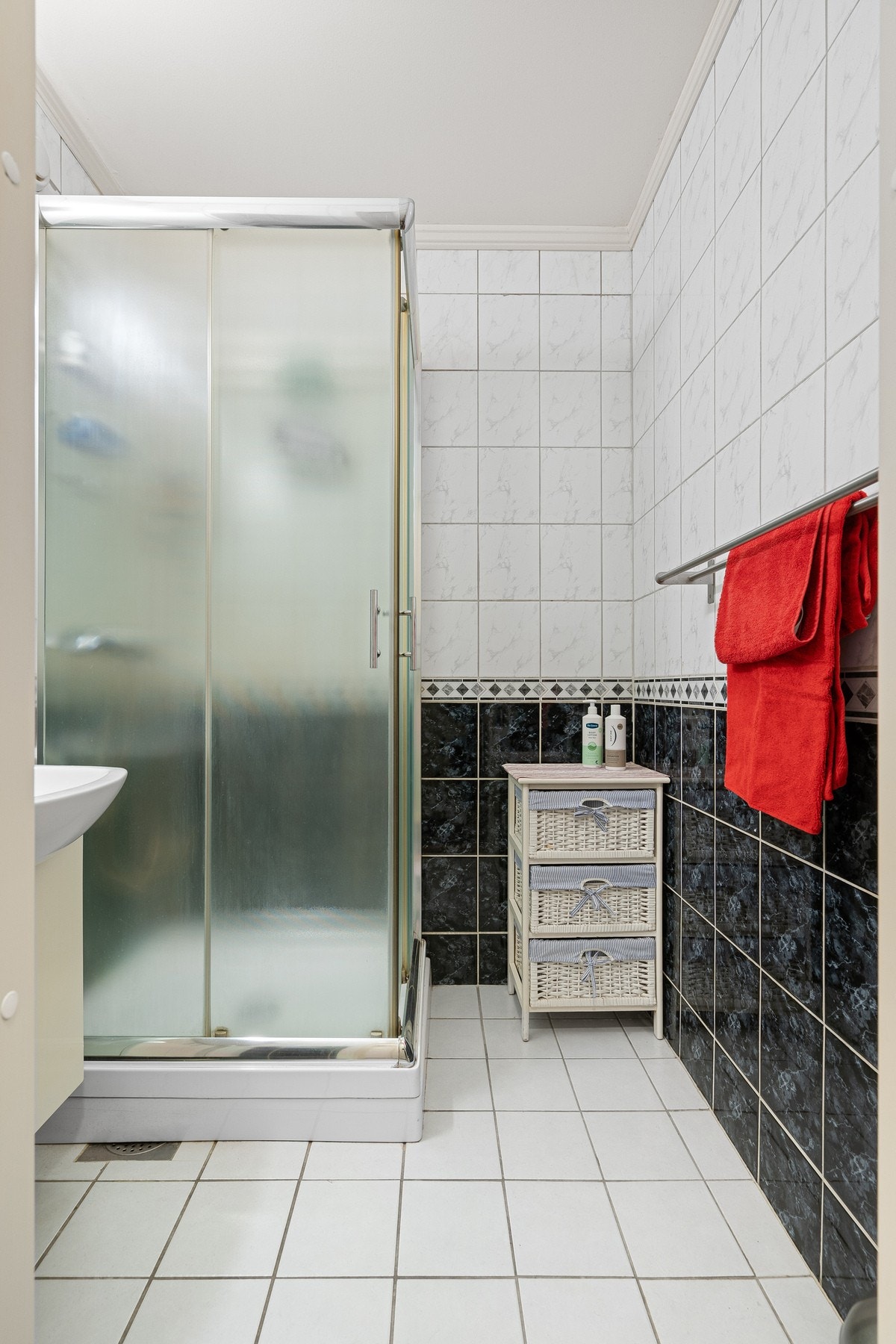 Flislagt bad, utstyrt med dusjkabinett og servant i skap. Galleribilde