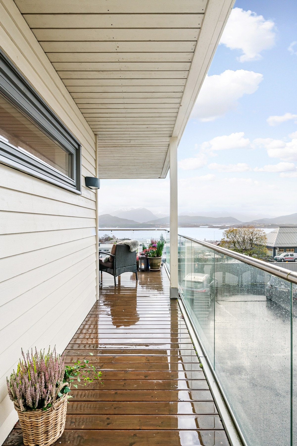 Pent dekke av terrassebord og elegant glassrekkverk. Legg også merke til lampe på vegg. Galleribilde