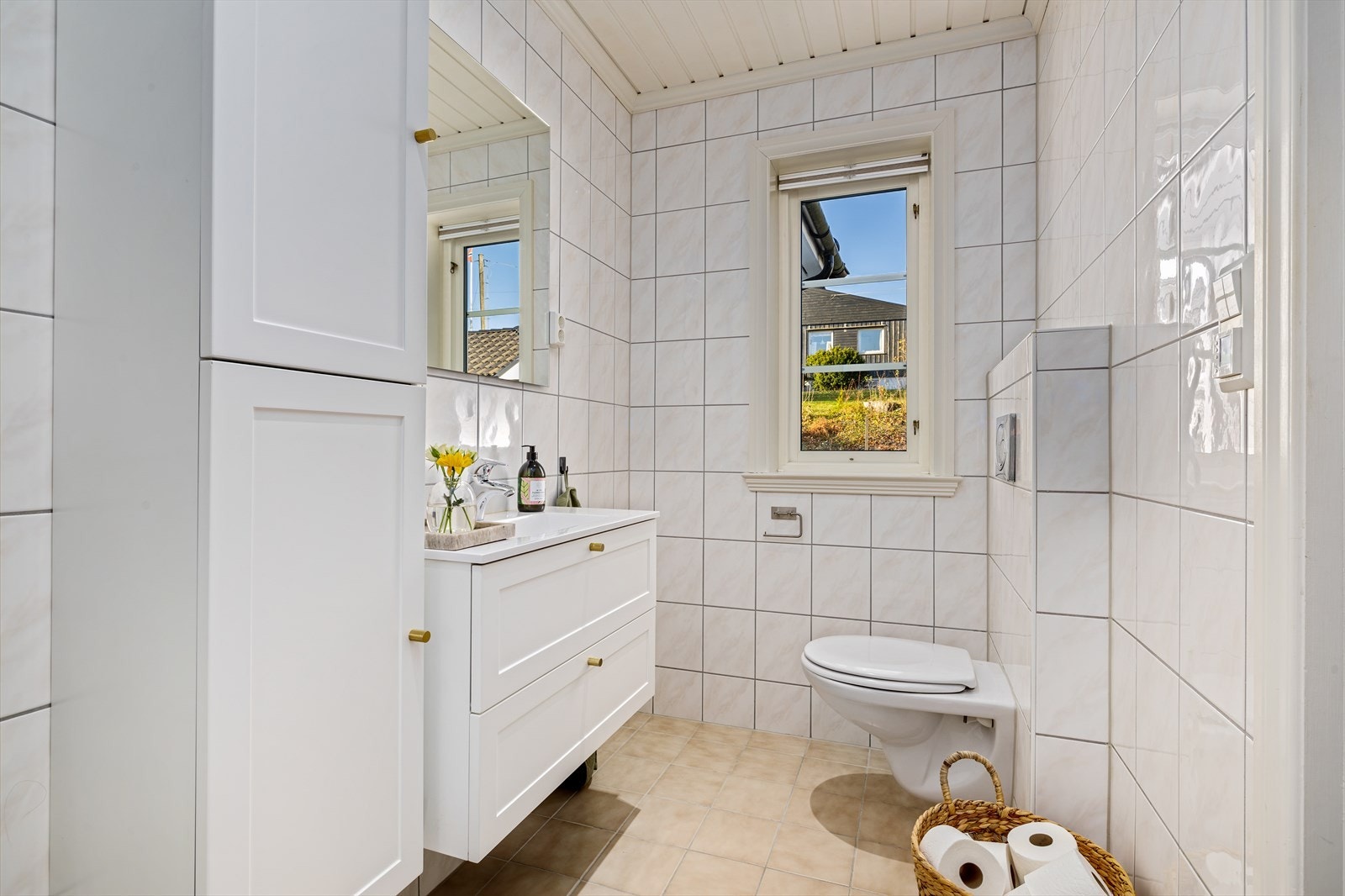 Eget flislagt bad i forbindelse med hovedsoverommet. Servant i skuffinnredning, høyskap, vegghengt toalett og dusj med glassvegg. Galleribilde