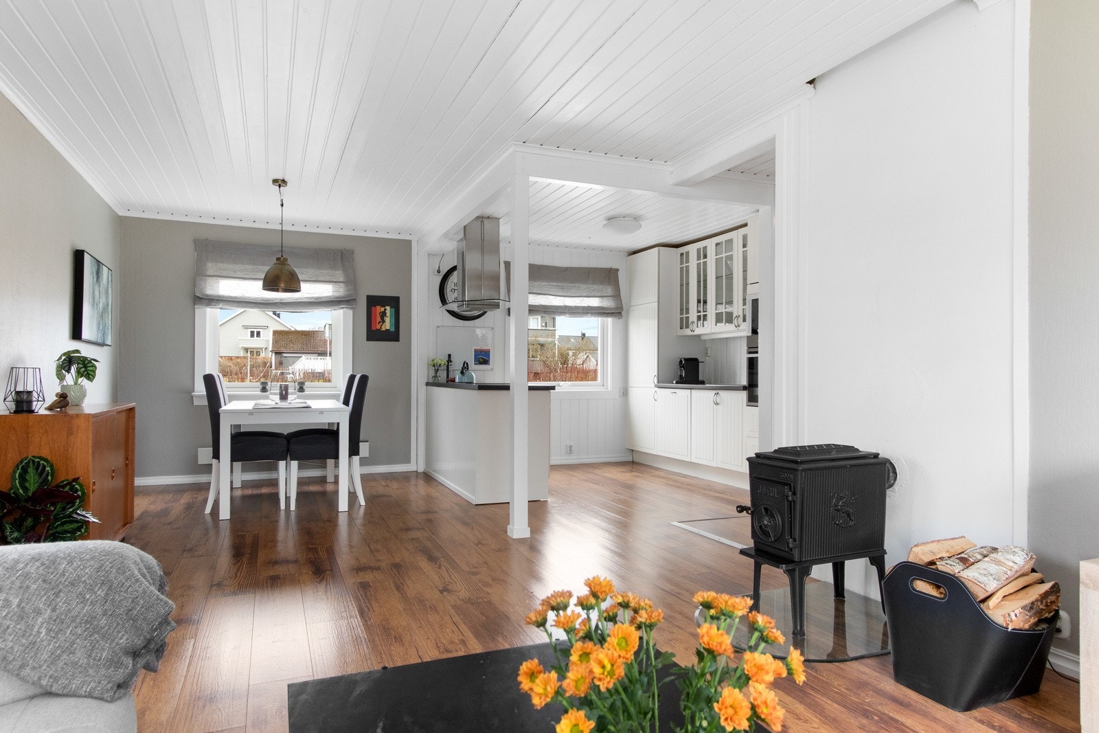 Laminatgulvet på kjøkkenet flyter sømløst over i stuen - et avlangt rom med gode lysforhold og beigemalte vegger. Galleribilde