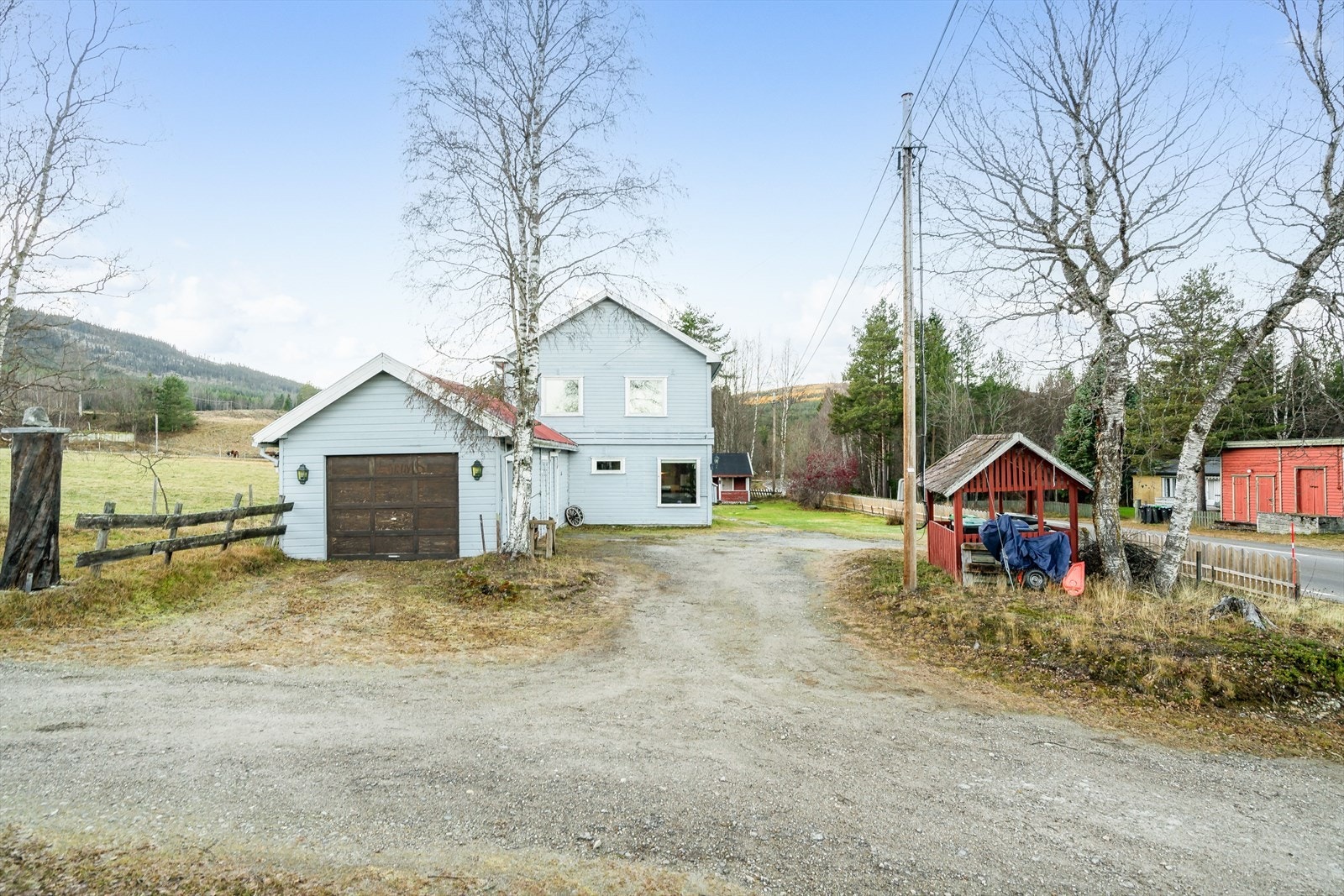 En solrik og landlig eiendom bebygd med stor enebolig og et eldre rødt anneks på 14m². Boligen har integrert garasje, bod og verksted. Galleribilde