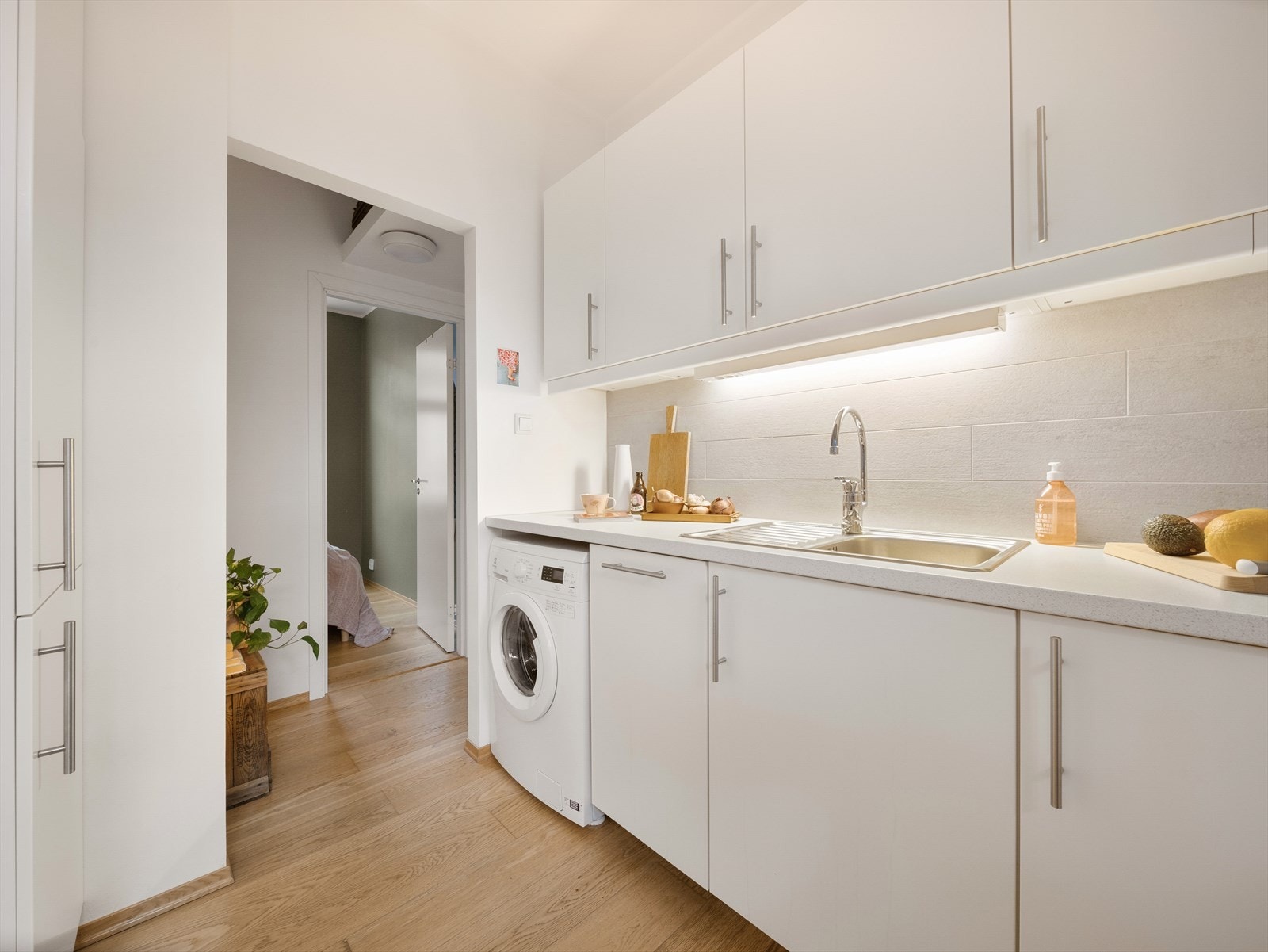 Kjøkkeninnredningen har en tidløs utførelse med hvite, slette fronter og laminat benkeplate Galleribilde