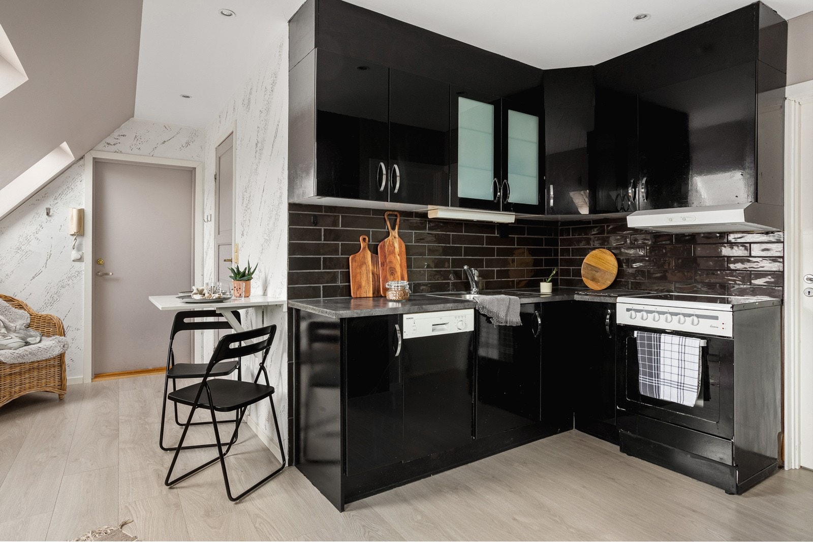 Kjøkkeninnredning har slette fronter, ett glasskap og laminat benkeplate med nedfelt vask av stål. Galleribilde