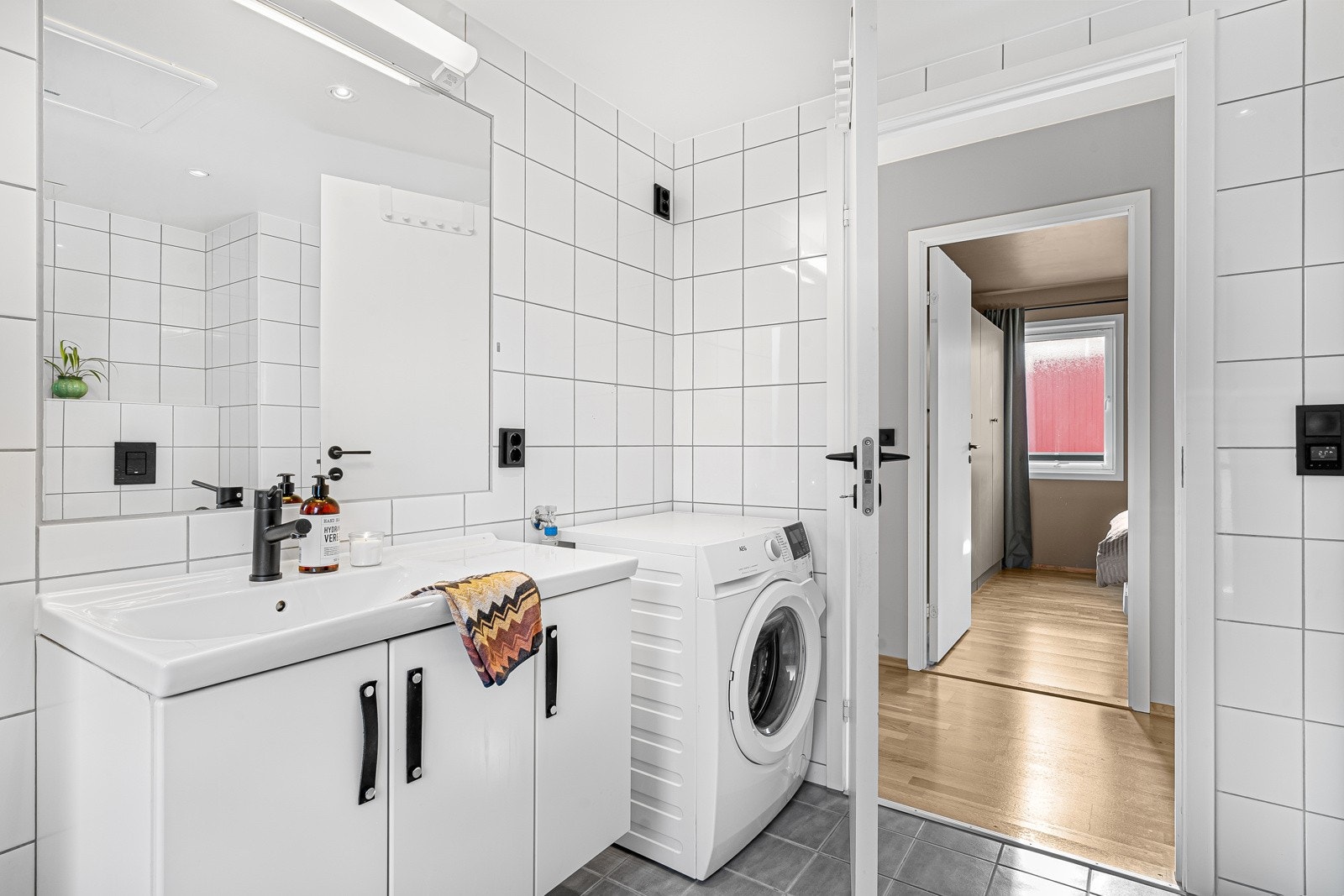 Pent, flislagt baderom med opplegg for vaskemaskin og tørketrommel. Galleribilde