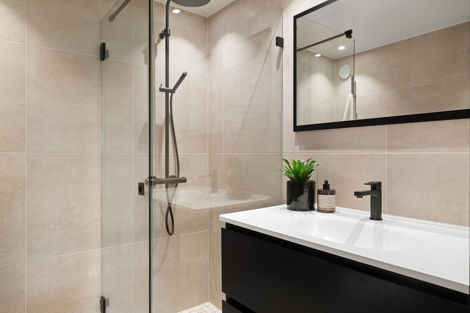 Badet er utstyrt med mekanisk avtrekk, innfellbare dusjdører, veggmontert wc og servantskap med ett greps blandebatteri fra Tapwell Galleribilde