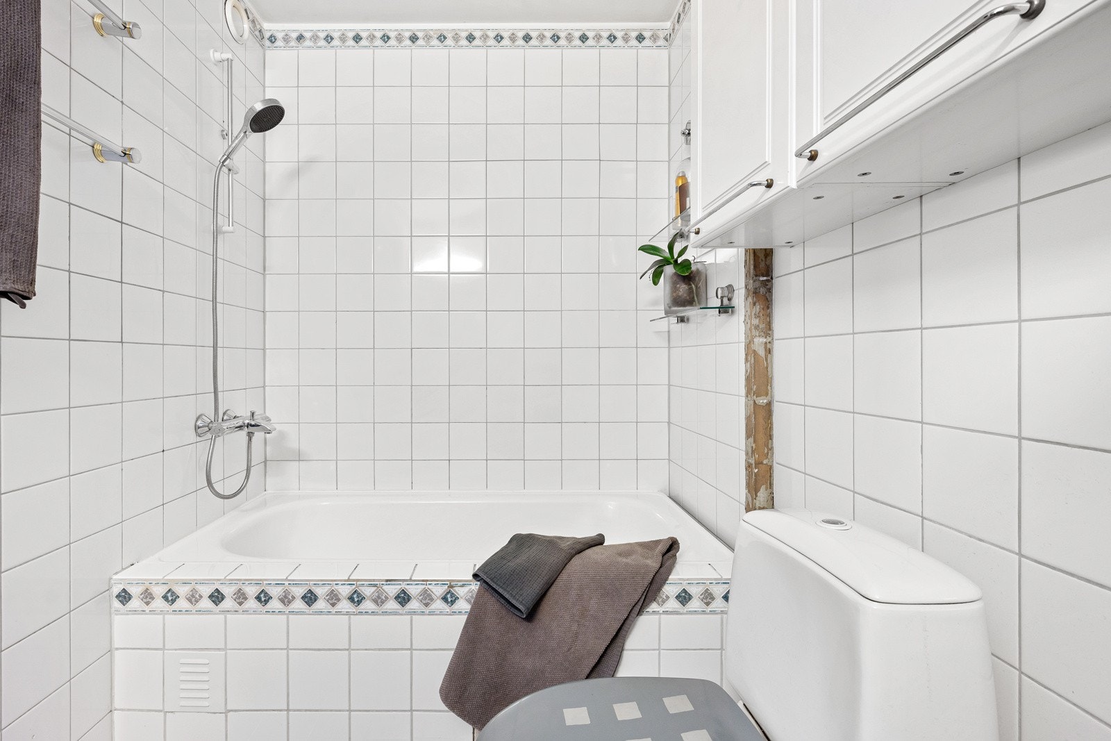 Badet har flislagte overflater, god skapplass, gulvvarme og et innfliset badekar med dusjløsning. Galleribilde