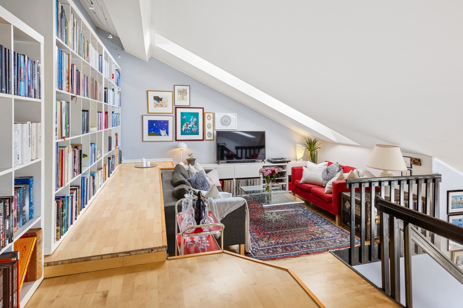 Mesaninen har plassbygde, lave skap, parkettgulv og spotbelysning langs innerste vegg. Galleribilde