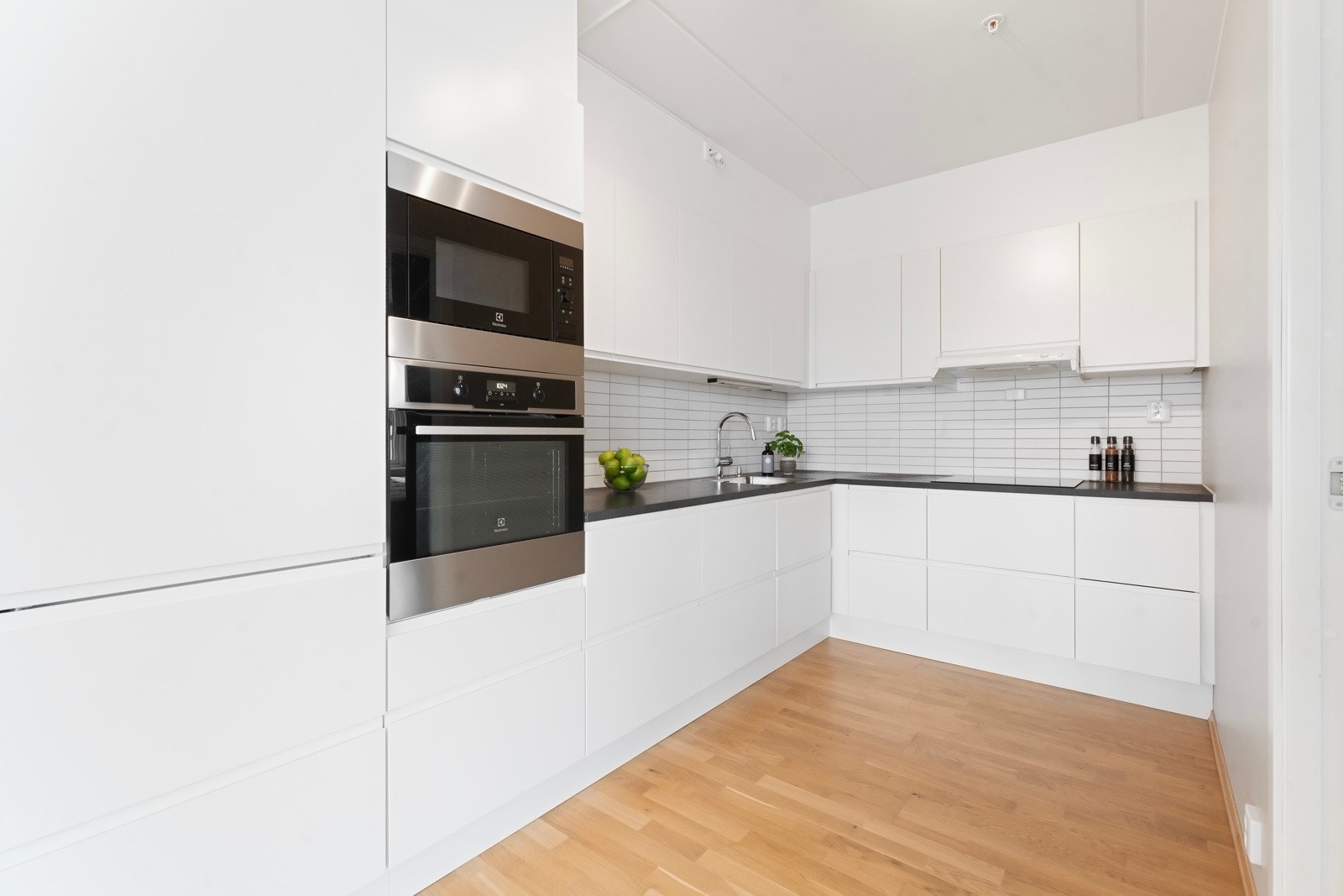 Kjøkken i egen sone med stilren takhøy kjøkkeninnredning med slette fronter og laminat benkeplate Galleribilde