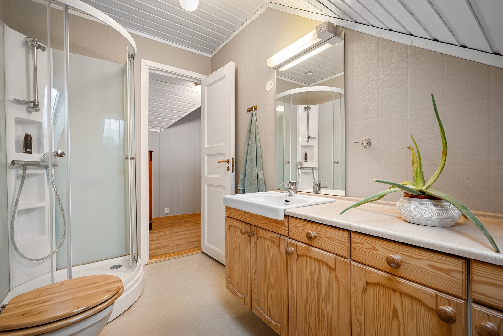 Badet på loftsetasjen inneholder dusjkabinett, toalett og servantinnredning Galleribilde