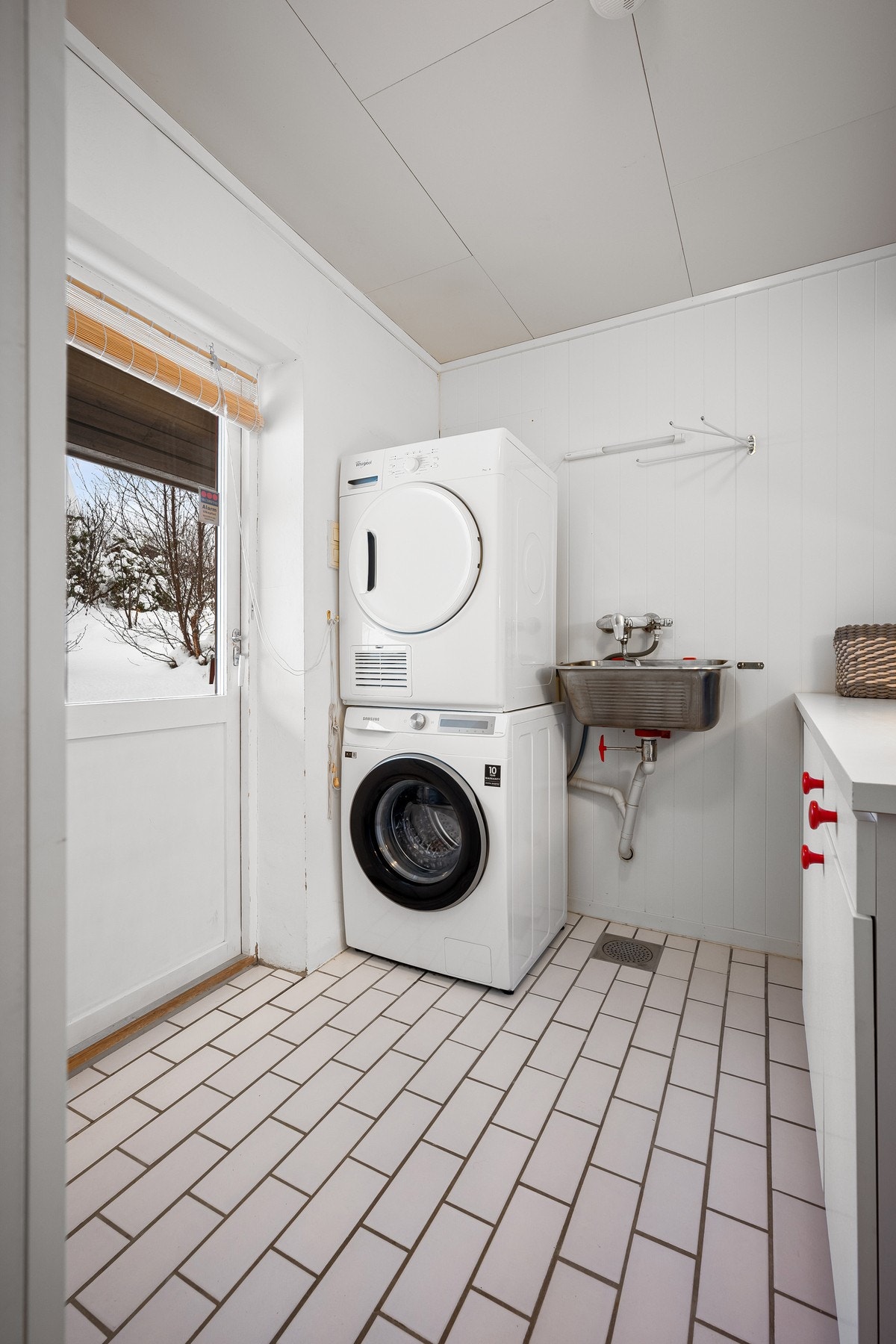 Vaskerommet har flislagt gulv med varme og inneholder skyllekar, innredning og opplegg for vaskemaskin Galleribilde