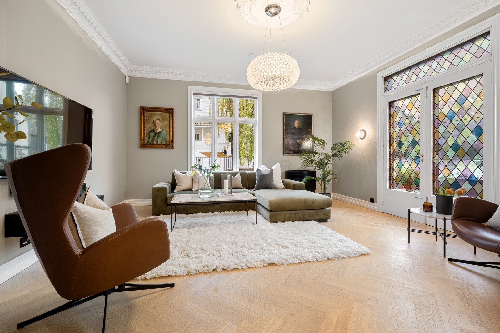 Klassisk stukkatur, vakker takrosett og terrassedører med fargede blyglassvinduer står i nydelig kontrast til den moderne, nyoppussede stilen, og de lysegrå veggene fremhever det eksklusive fiskebeinsparkettet på beste måte. Galleribilde