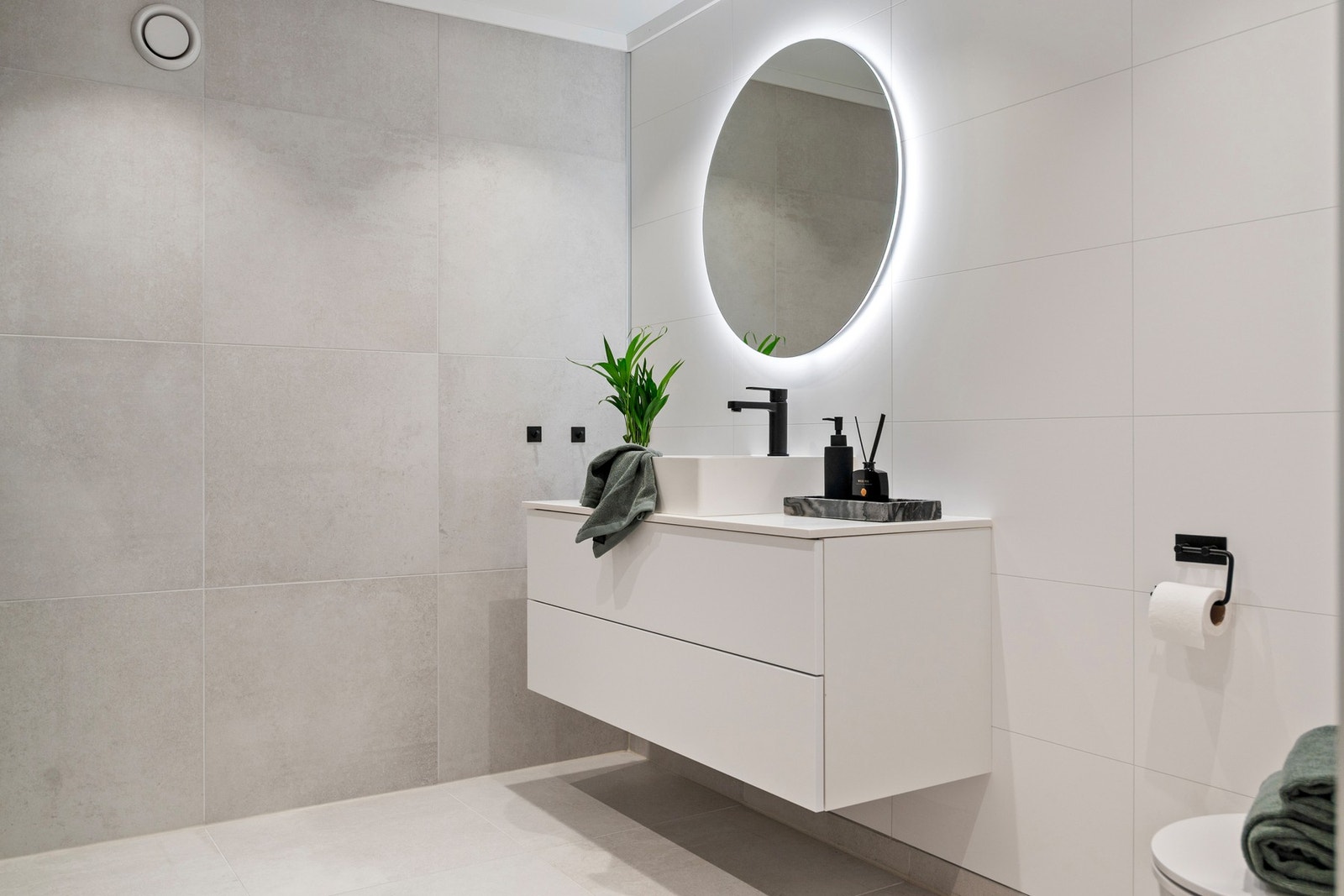 Det er innredet med vegghengt toalett, dusjhjørne, og servant med møblement og speil. Galleribilde