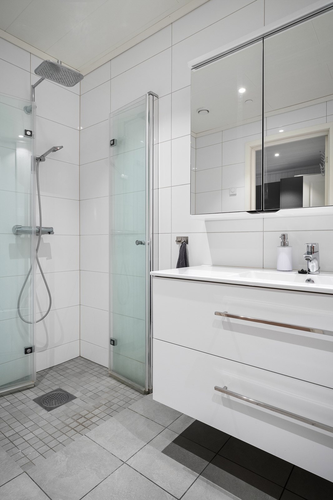 Badet er utstyrt med vegghengt toalett, dusjhjørne med innfellbare dører, servant m/servantskap og opplegg for vaskemaskin. Galleribilde