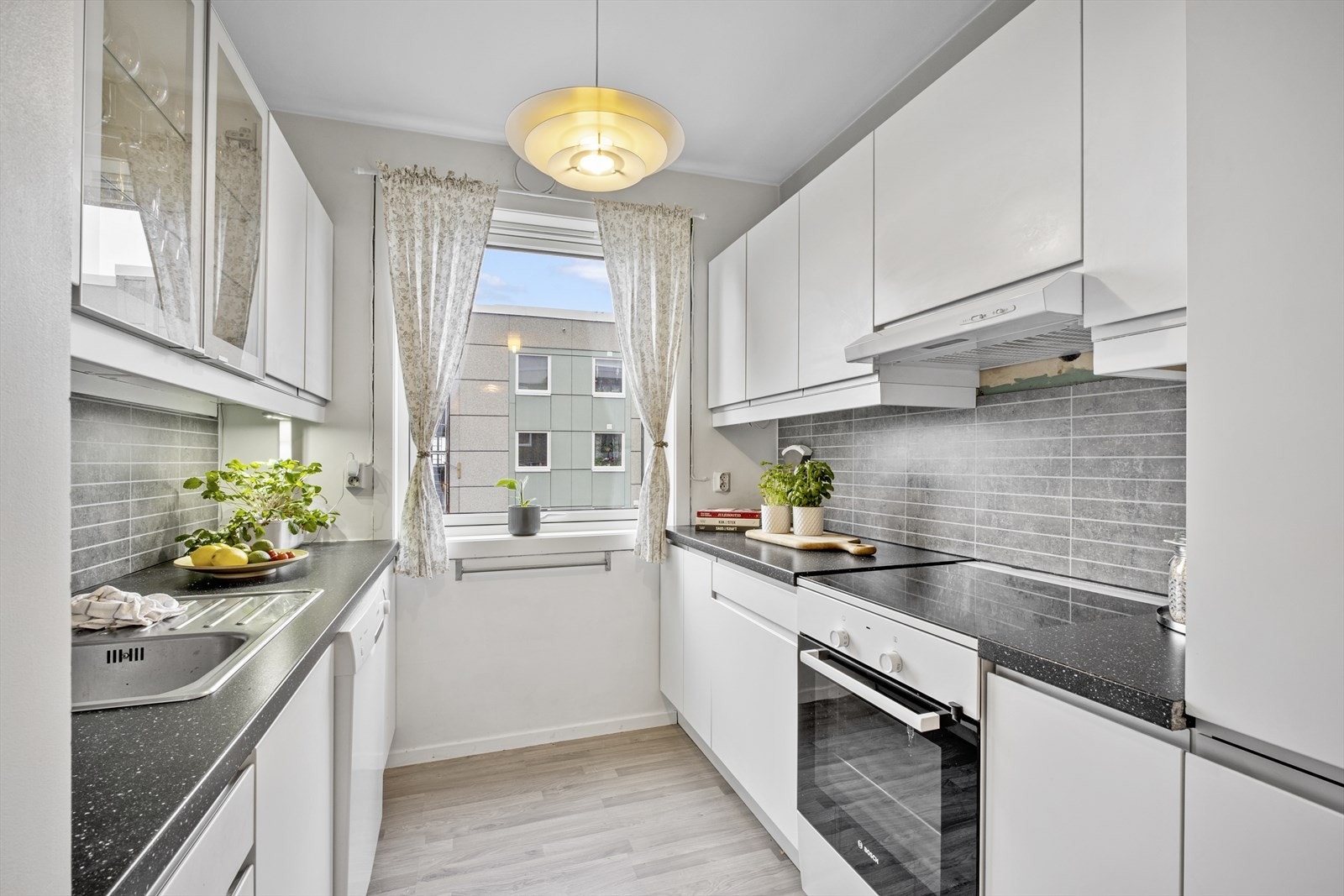 Kjøkkenet er innredet med slette hvite fronter og laminert benkeplate Galleribilde