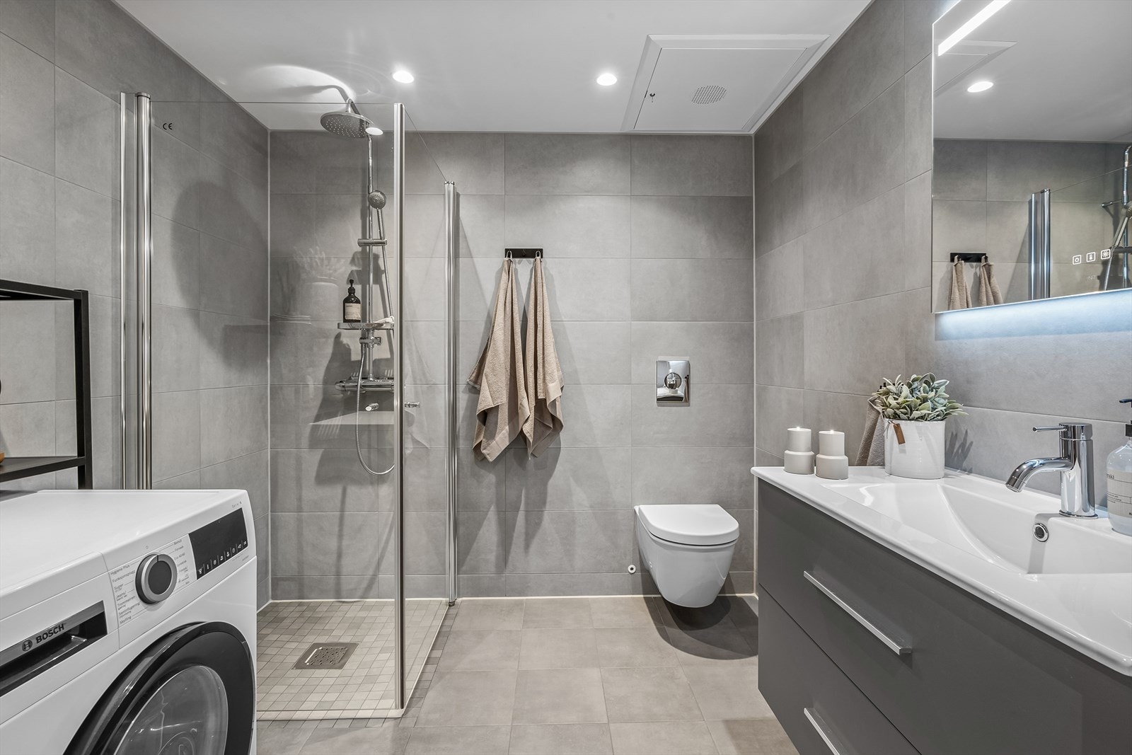 Stort og lekkert baderom med brede fliser på vegg og innfelt downlights i himling. Galleribilde