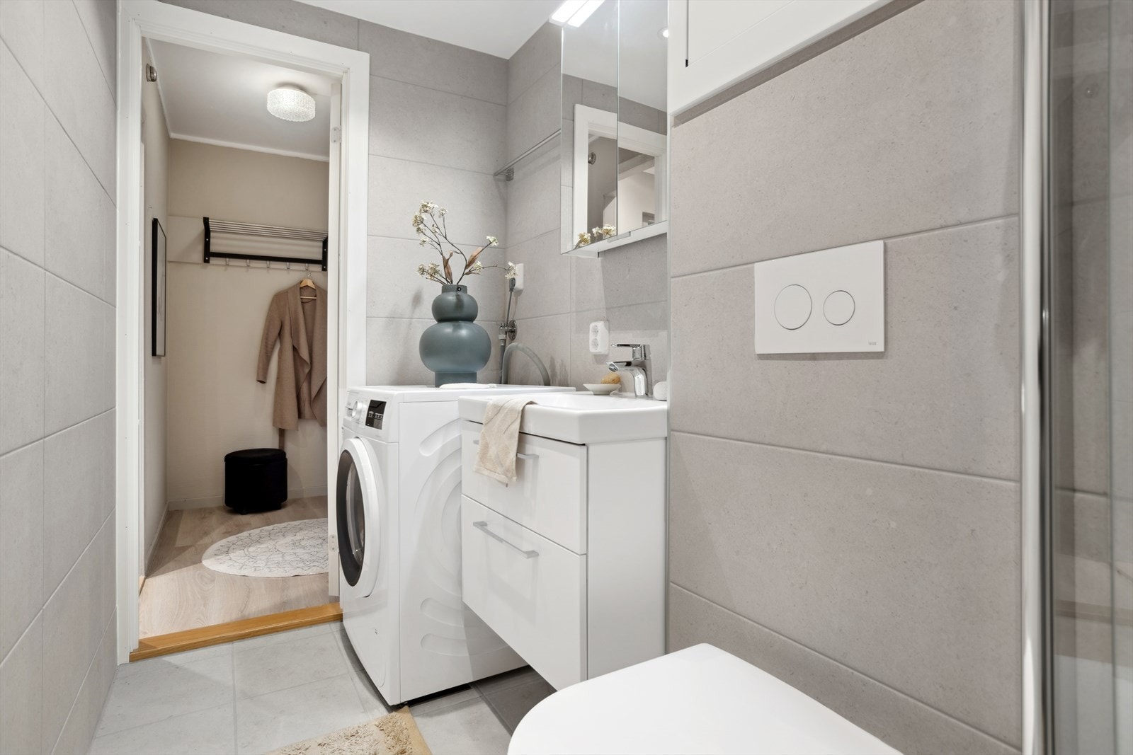 Badet er utstyrt med dusj, opplegg for vaskemaskin, servant med innredning og vegghengt toalett. Galleribilde