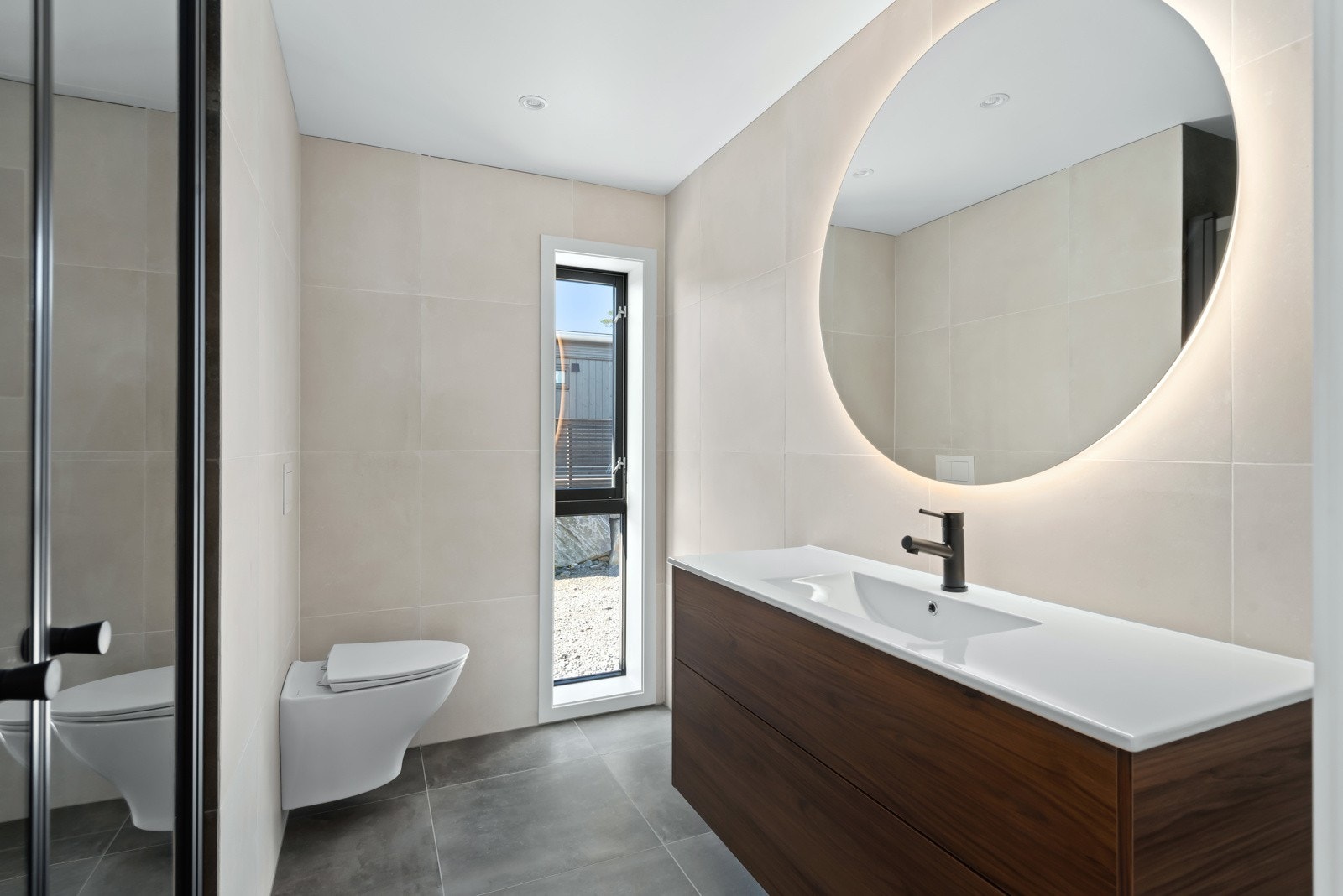 Baderom med gjennomført fargepalett. Stort speil med lys og servant med skuffeløsning. Galleribilde