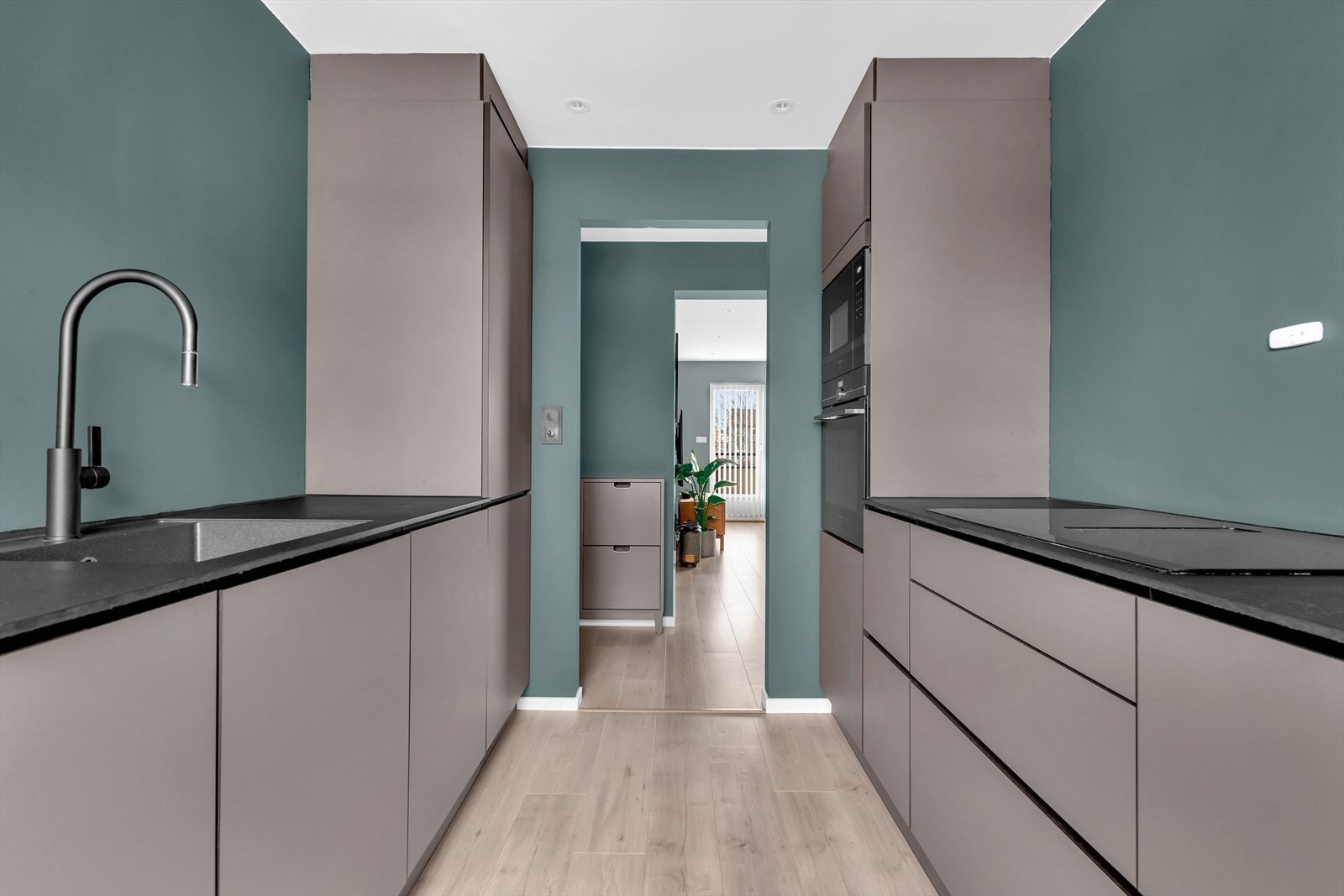 Videre, fra kjøkkenet og gjennom gangen glir planløsningen sømløst over til stuen, noe som skaper en flott og sammenhengende romfølelse. Galleribilde