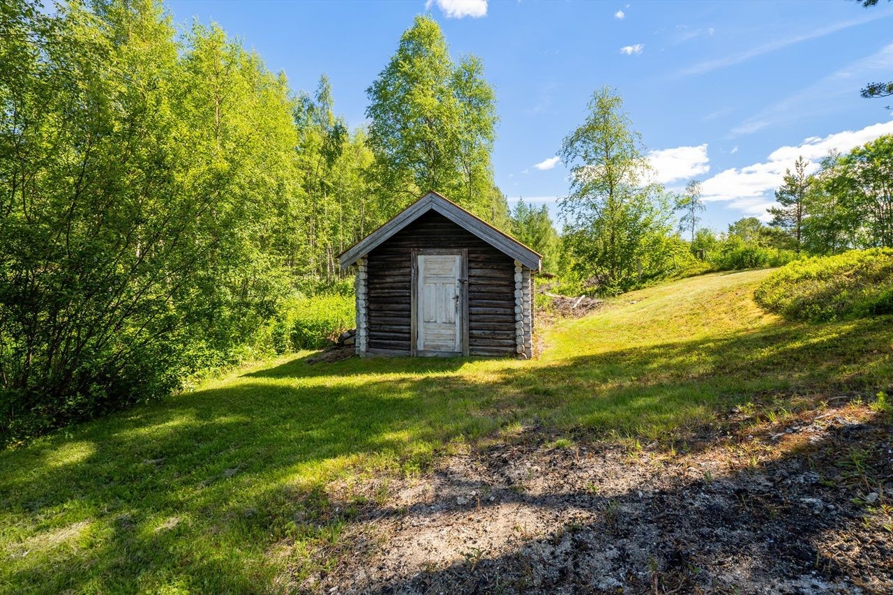 På eiendommen står en laftet hytte og et uthus. Galleribilde