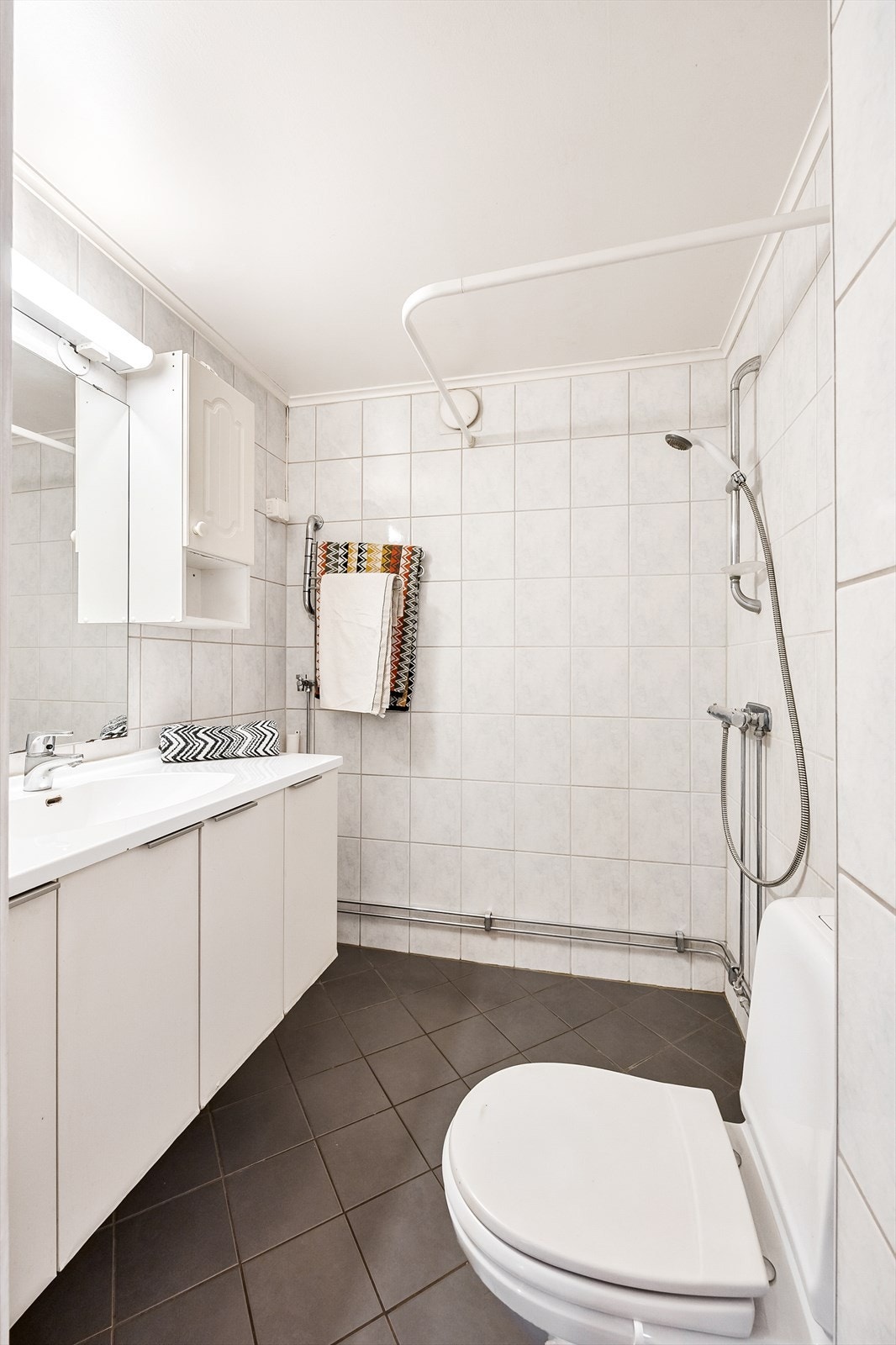 Badet er utstyrt med gulvstående wc og servantinnredning med under- og overskap. Galleribilde