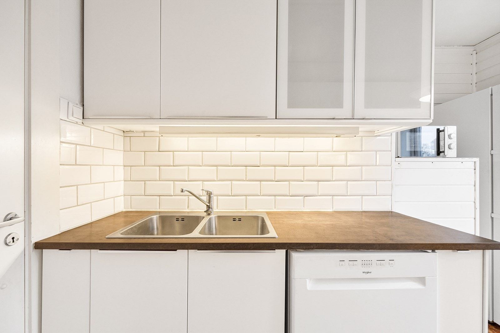 Innredningen har hvite slette fronter, frostede vitrineskap og laminerte benkeplater. Galleribilde