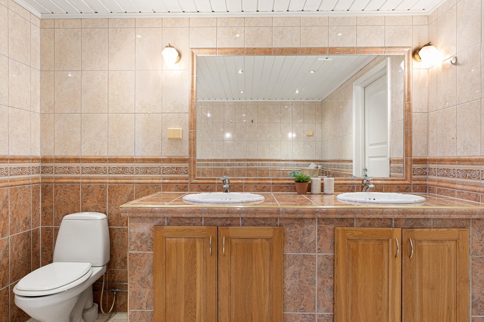 Badet består av gulvmontert toalett, to servanter med oppbevaringshyller og frittstående badekar Galleribilde