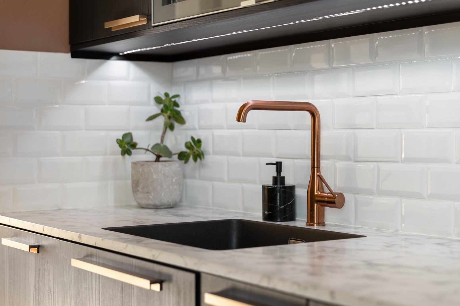 Nedfelt oppvaskkum i kompositt - flislagt mellom benkeplate og overskap med stikkontakter samt belysning over benkeplate Galleribilde