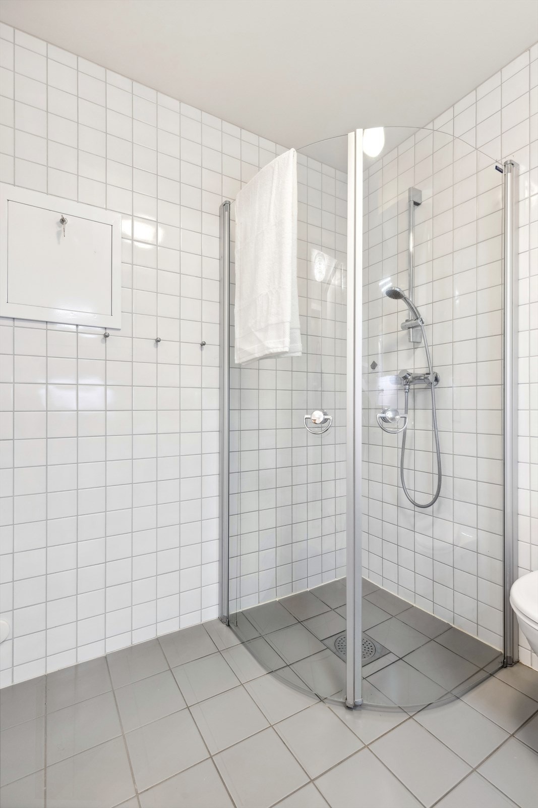 Stor og romlig dusj med vendbare dører. Det er elektriske varmekabler i gulvet og opplegg til vaskemaskin Galleribilde