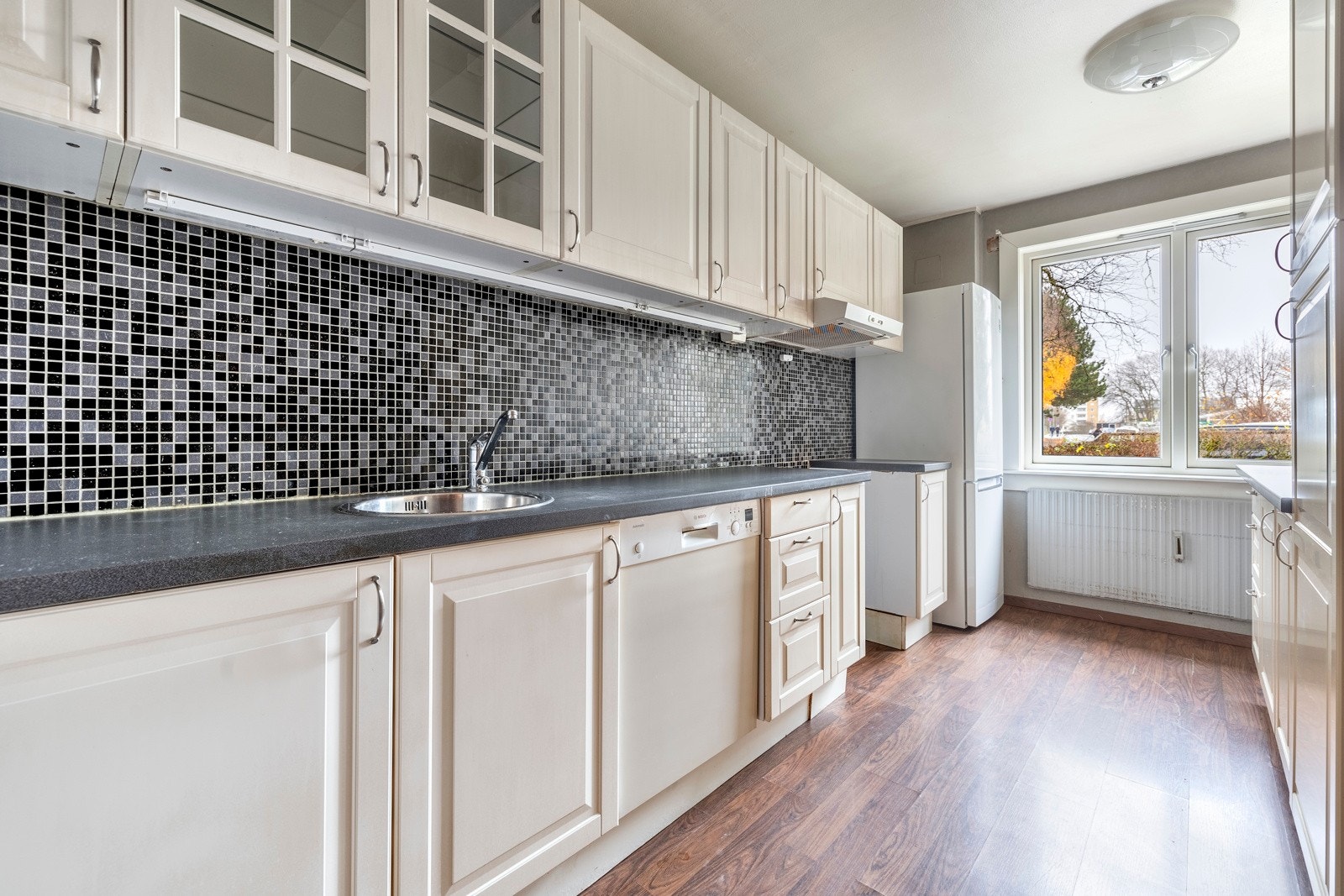 Kjøkkenet er innredet med lyse profilerte fronter og benkeplater av laminat med nedfelt kum. Galleribilde