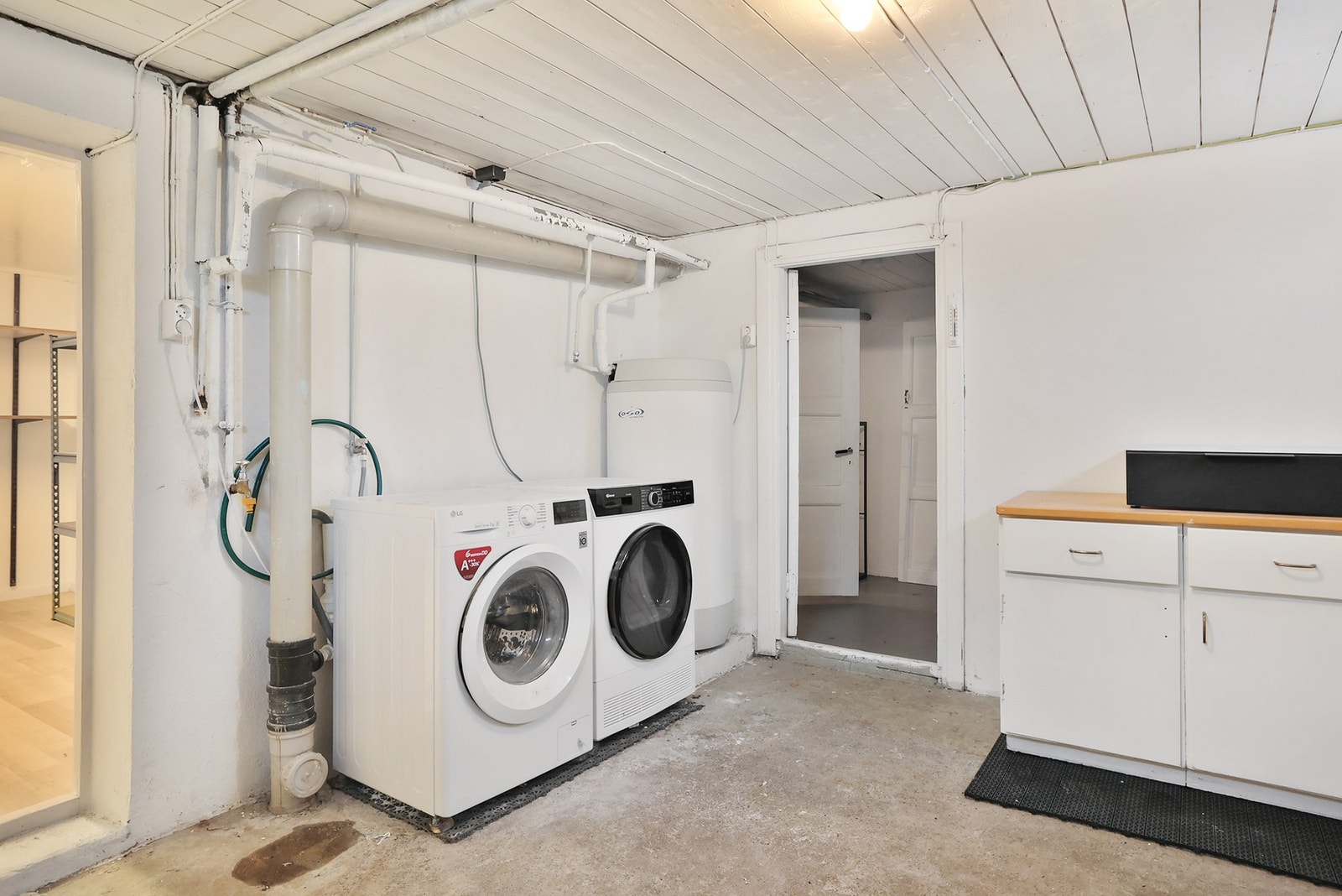 Vaskerommet har betonggulv og veggflater av malt mur. Det er opplegg for vaskemaskin. Galleribilde