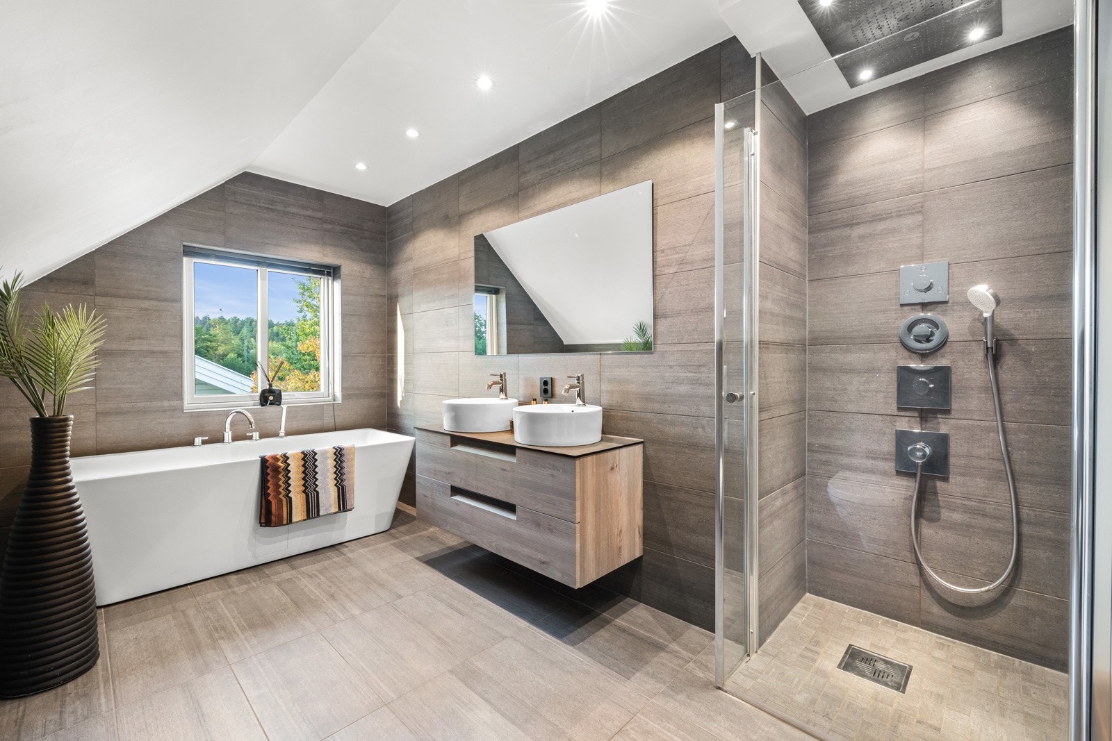 Badet er utstyrt med et vegghengt servantskap med skuffer, et delikat frittstående badekar og vegghengt toalett. Galleribilde