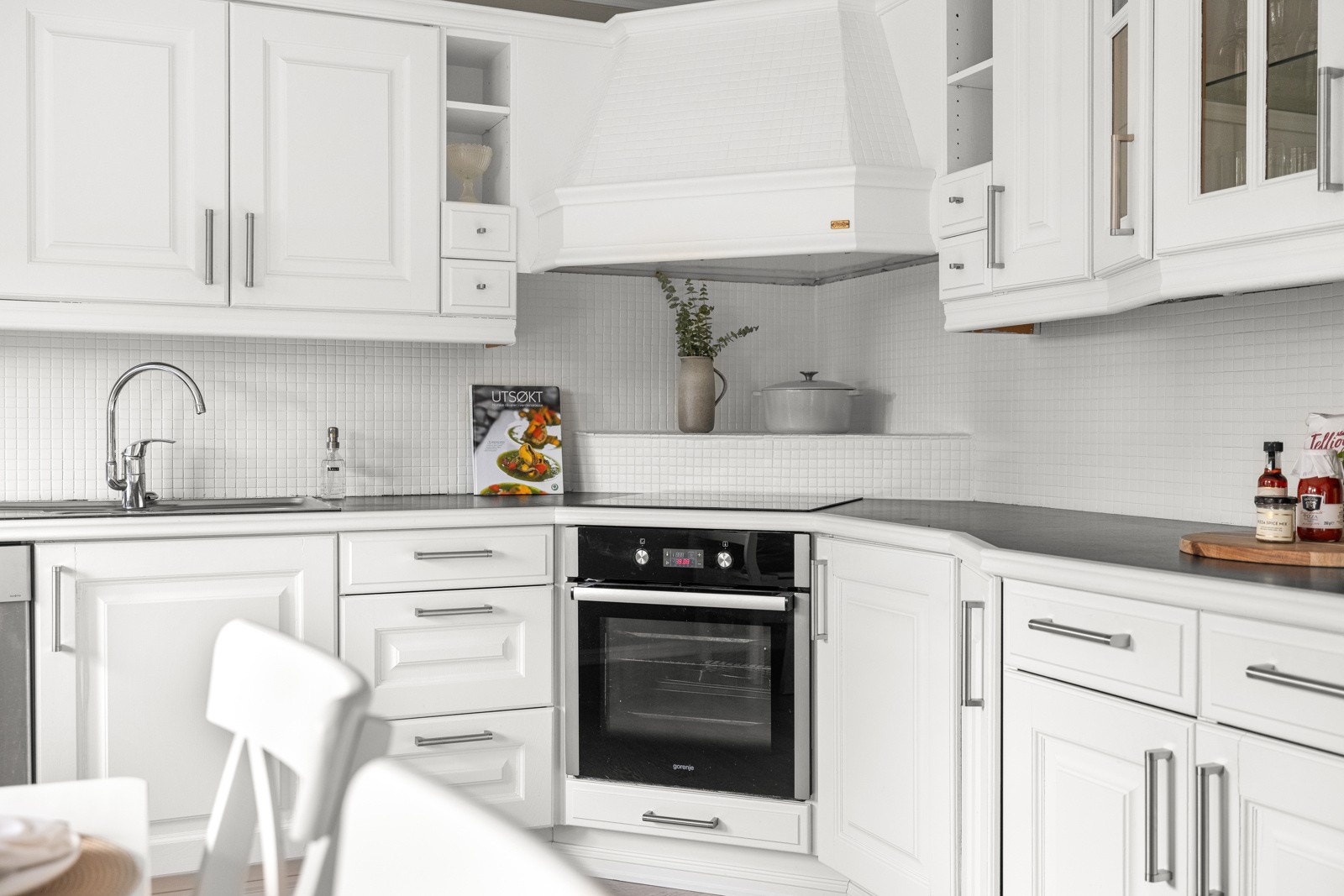 Veggen mellom benkeplaten og overskapene er flislagt med mindre hvite fliser som gir et rent og helhetlig inntrykk av rommet. Galleribilde