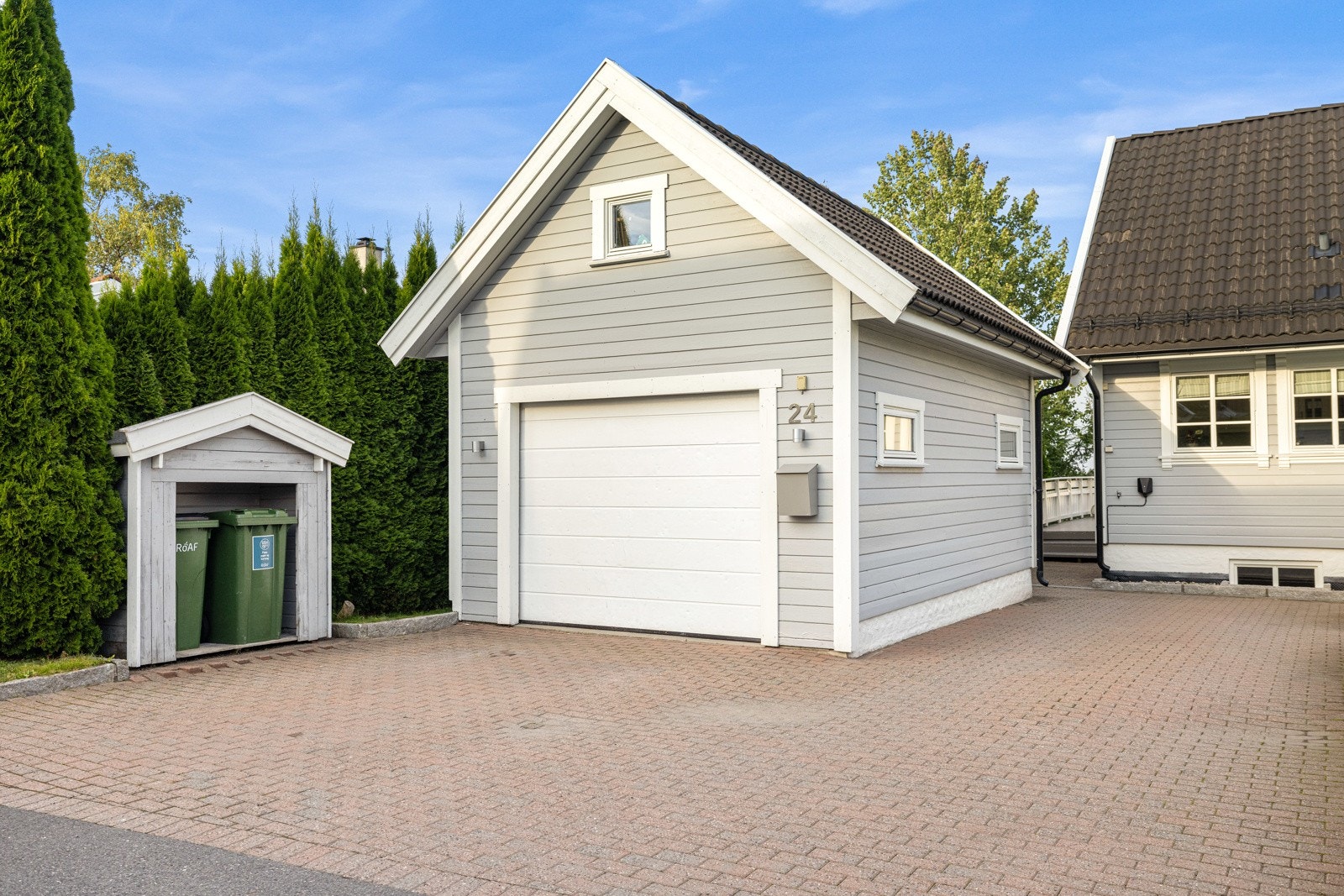 Boligen har en flott steinlagt gårdsplass og garasje med elbil-lader som ble montert i 2022. Galleribilde
