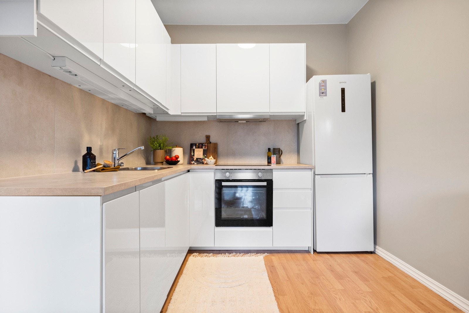 Glatt kjøkkeninnredning med god skap- og benkeplass og opplegg for oppvaskmaskin. Galleribilde