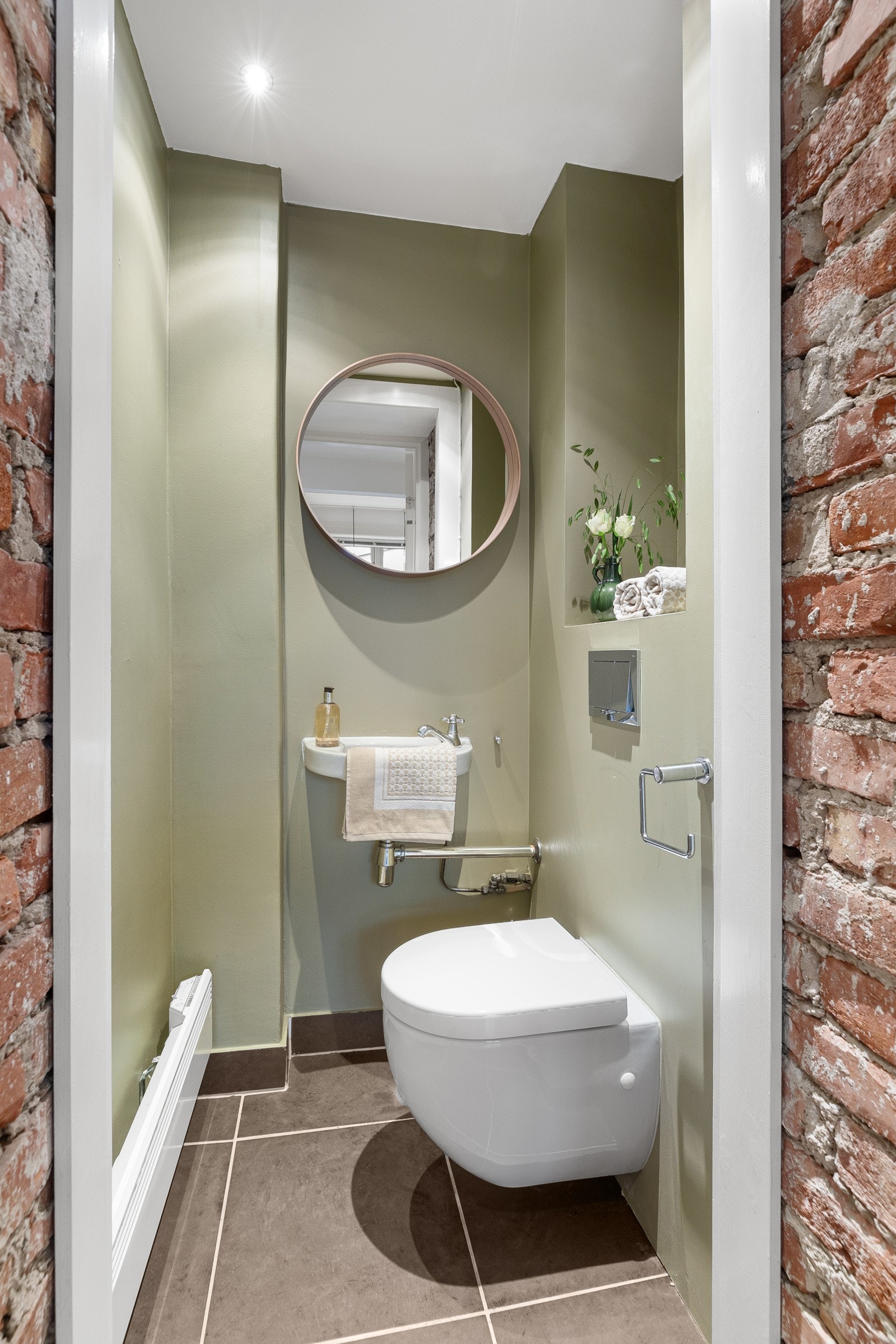 Leiligheten disponerer ett separat toalettrom med toalett, servant, rundt speil og toalett. Nisje for praktisk oppbevaring Galleribilde