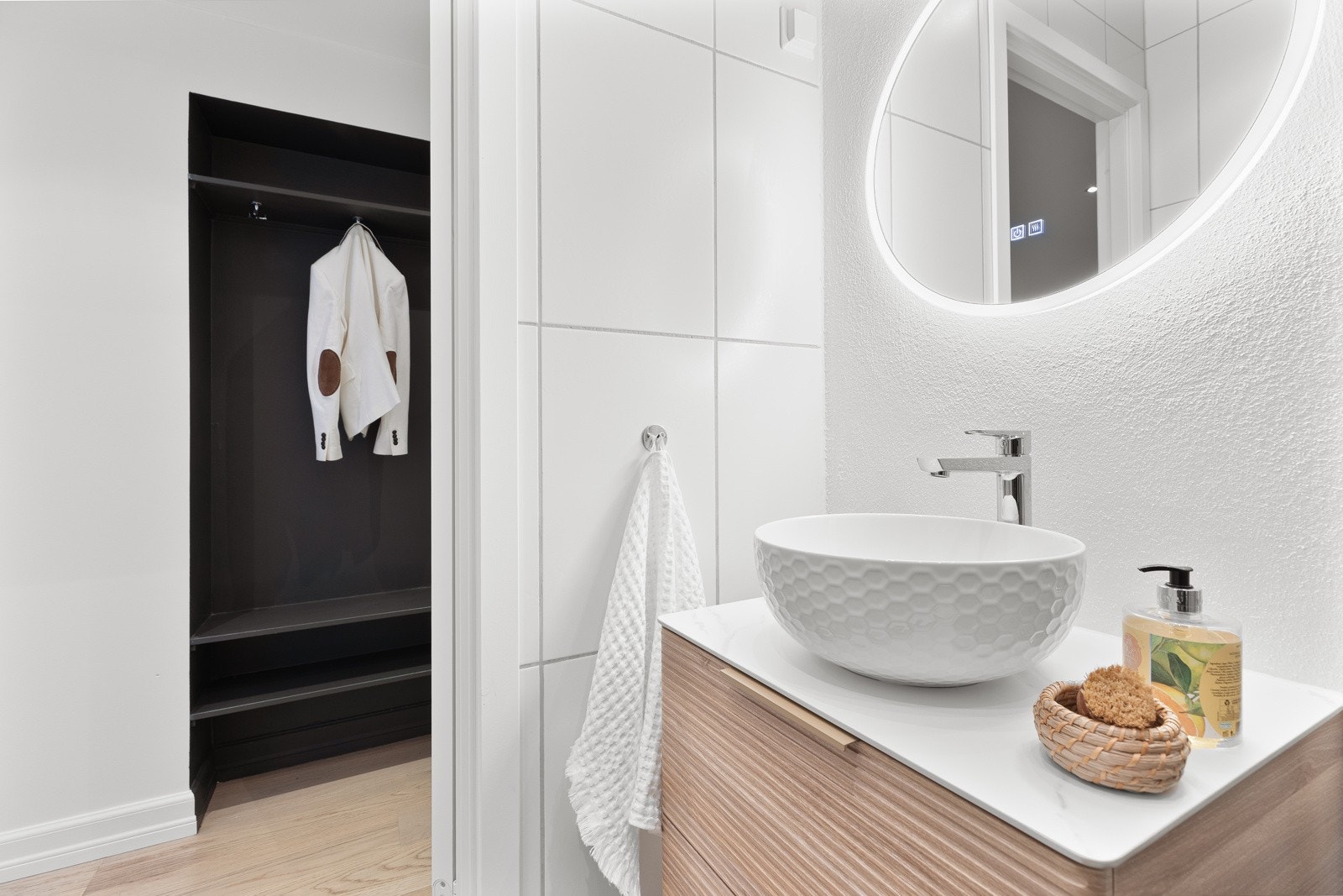 Innredningen består av servantskap med servantbolle, rundt speil med integrert belysning, hånkleholder montert på vegg og dusjhjørne med regnfallsdusj Galleribilde