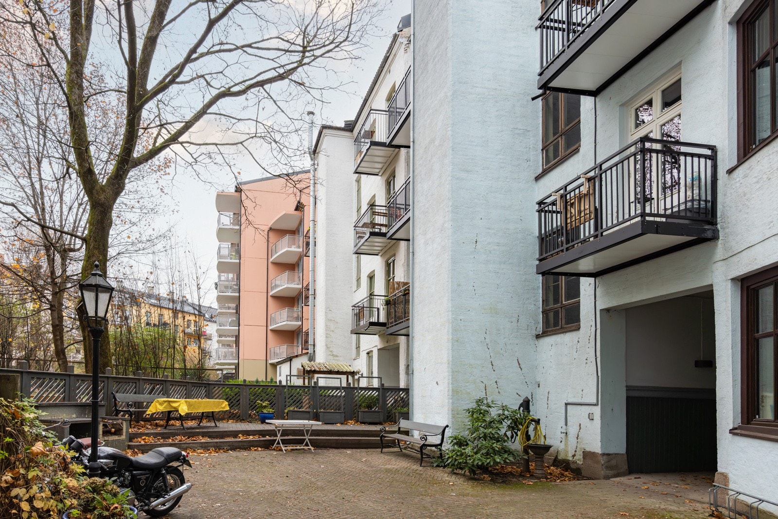 Pent opparbeidet bakgård med diverse sittegrupper, sykkelparkering og beplantning på sommerstid. Galleribilde