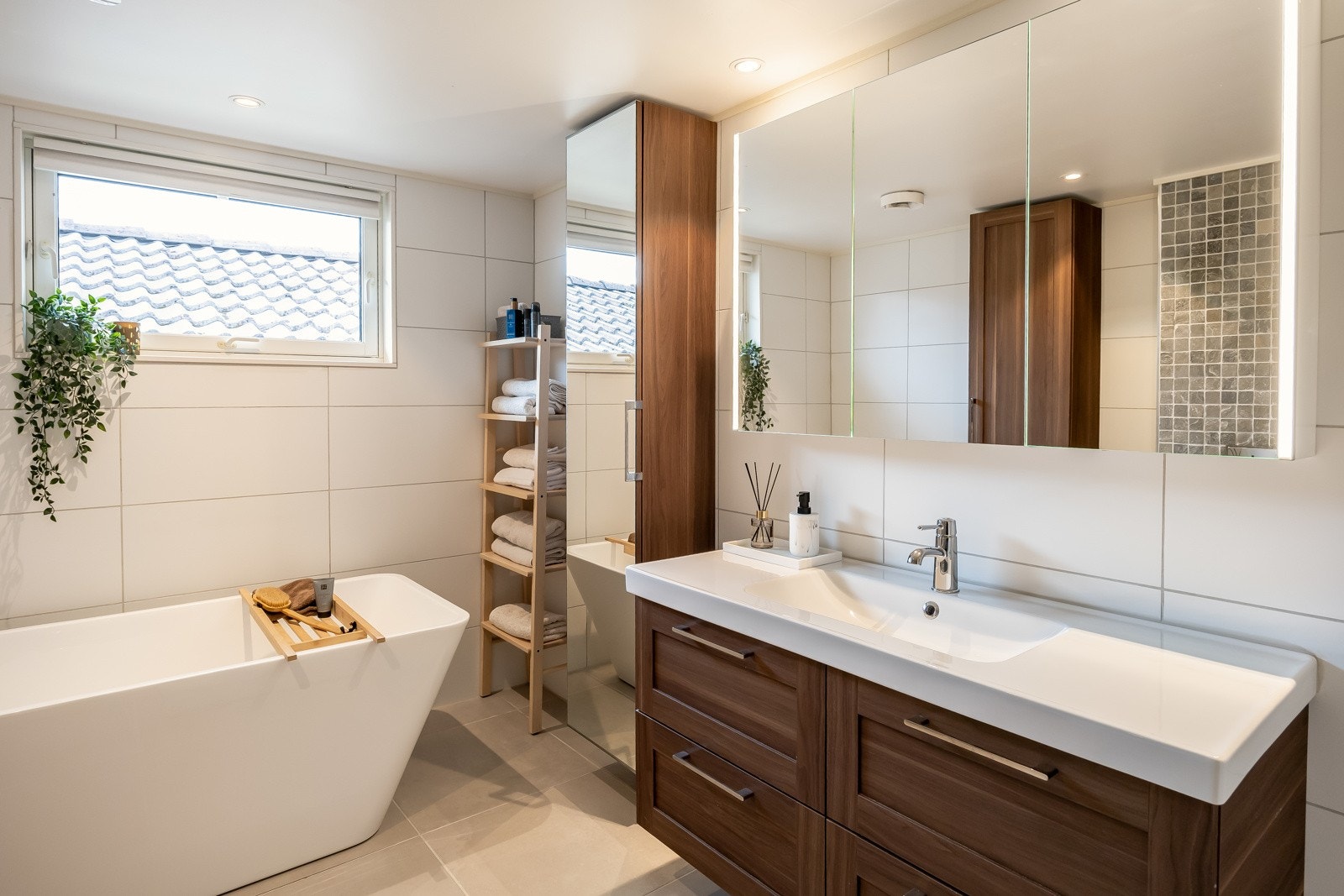 Badet har varmekabler i gulv, dusjvegger av glass, badekar, vegghengt toalett og servant Galleribilde