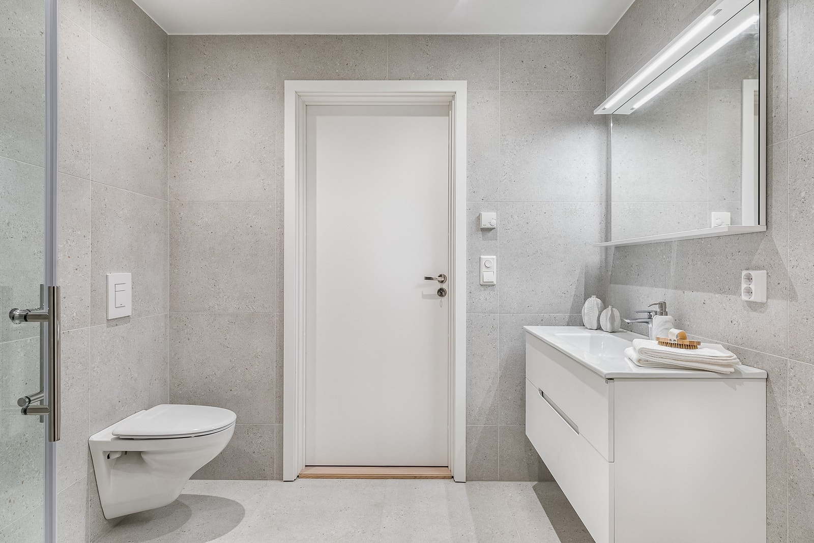 På badet er både gulv og vegger utført med tidsriktige terrazzo-fliser av storformat. Galleribilde