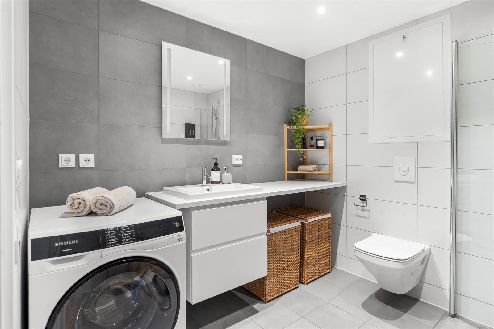 Badet er innredet med vegghengt klosett, servant nedfelt i benkeplate, speil med lys og dusjhjørne med svingbare glassdører. Det er opplegg for vaskemaskin og balansert ventilasjon. Galleribilde