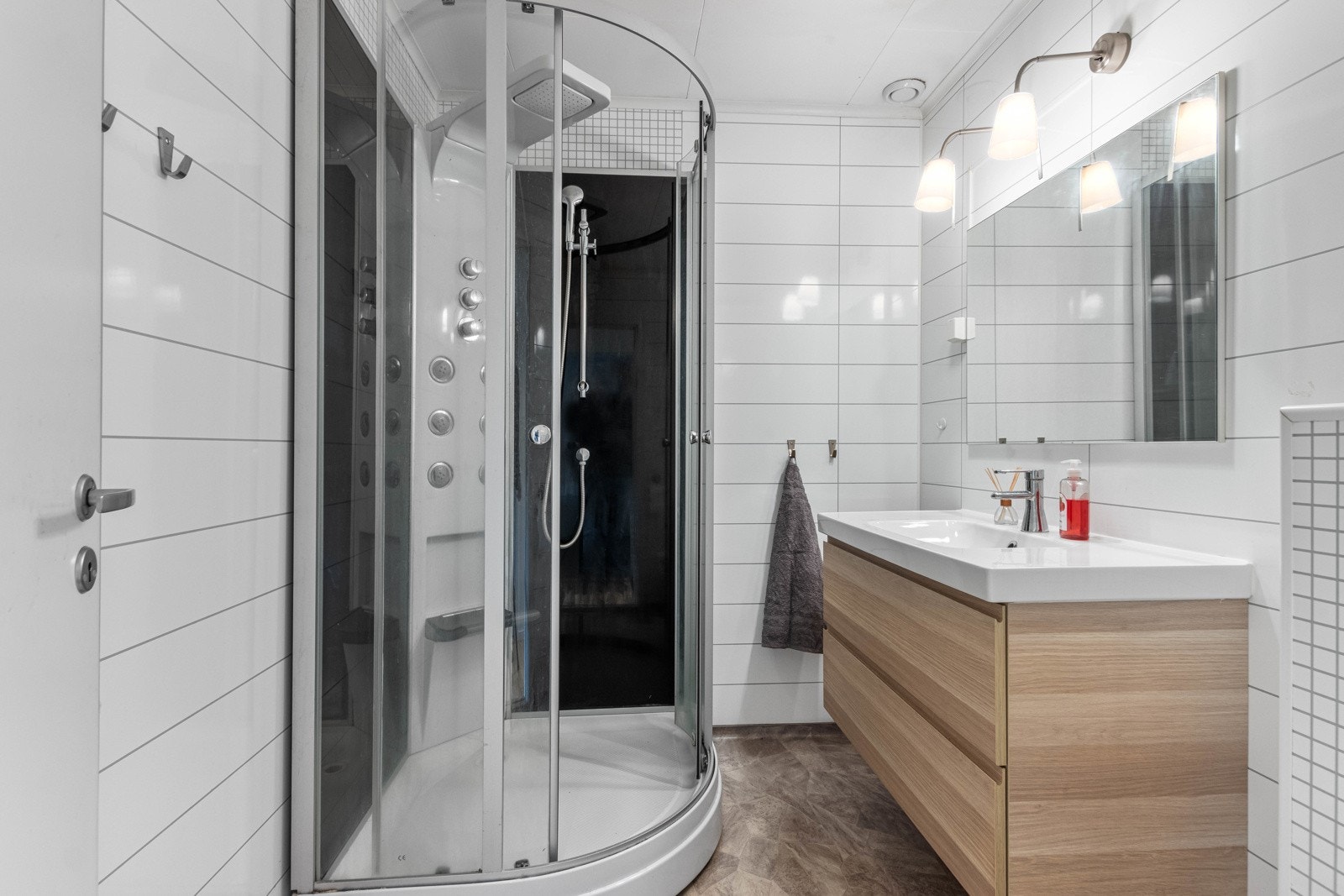 Lyst og pent bad med dusjkabinett, vegghengt wc og nedfelt servant med praktisk skuffeseksjon. Galleribilde