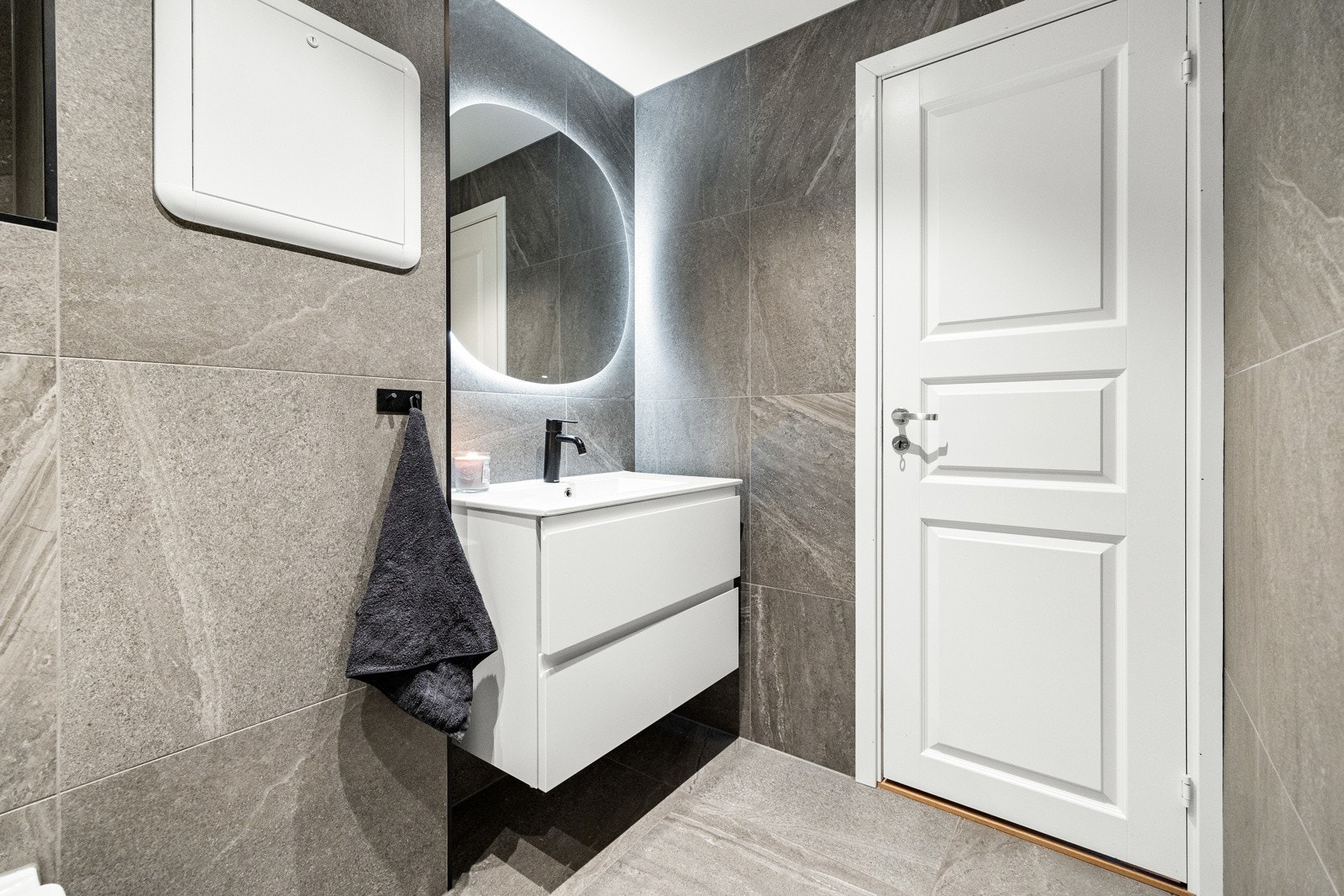 Badet inneholder vegghengt servantskap, vegghengt speil med lys, dusj, vegghengt toalett og opplegg for vaskemaskin. Galleribilde