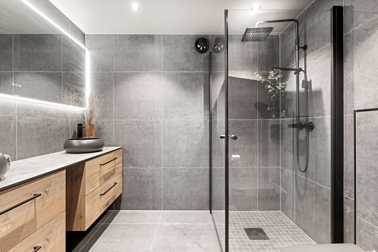 Flott bad som er utstyrt med vegghengt toalett, dusjhjørne, og innredning med dobbel servant Galleribilde