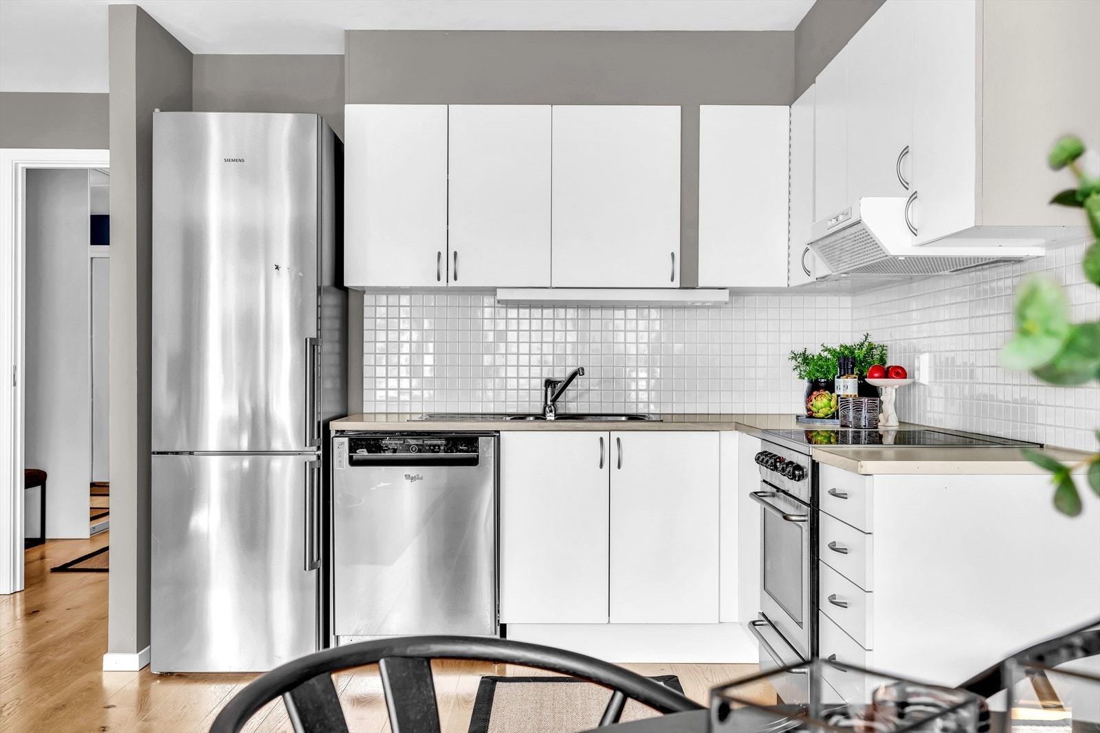 Moderne kjøkken med frittstående hvitevarer og flislagt vegg over benk Galleribilde