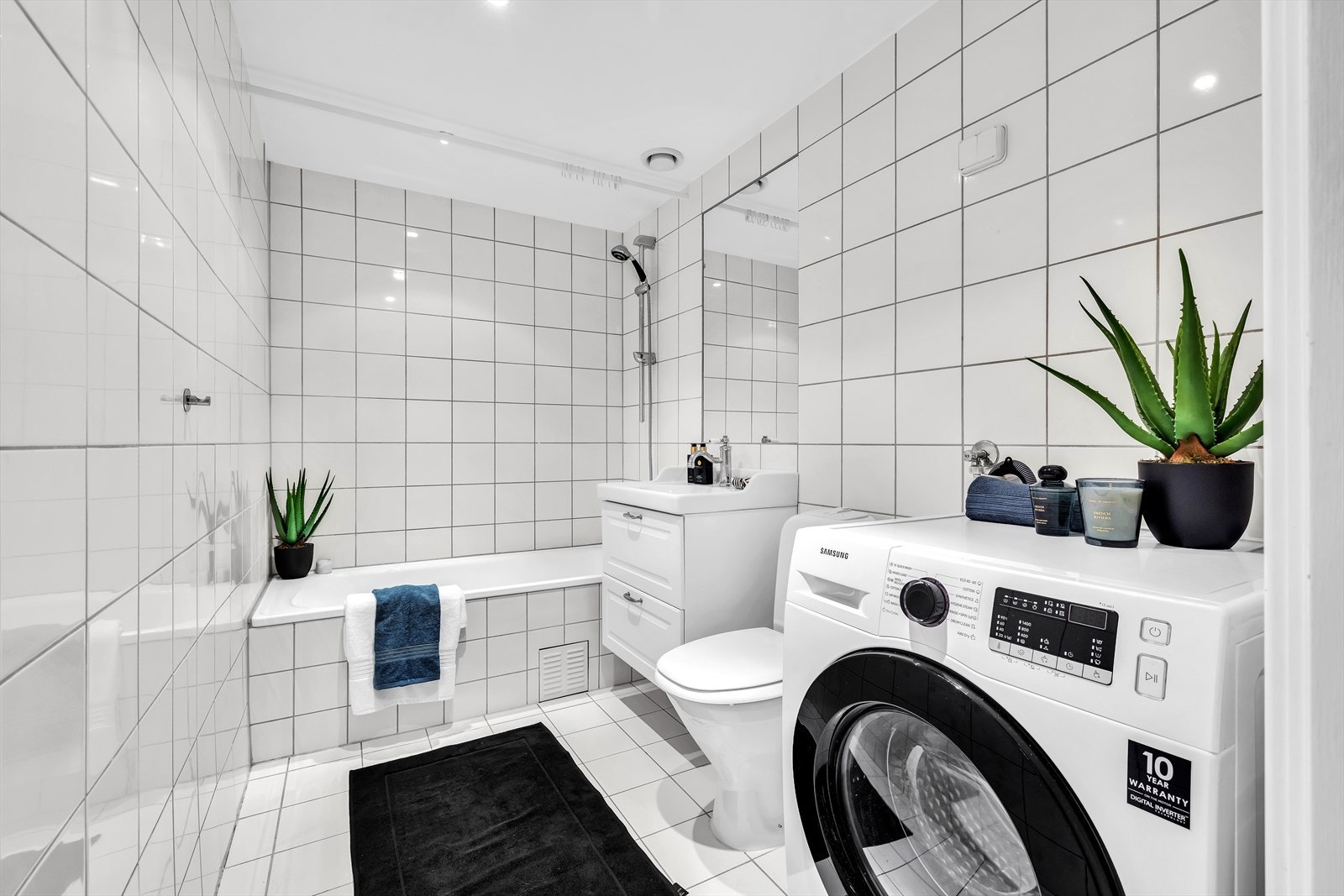 Flislagt bad med varmekabler, badekar og opplegg for vaskemaskin Galleribilde